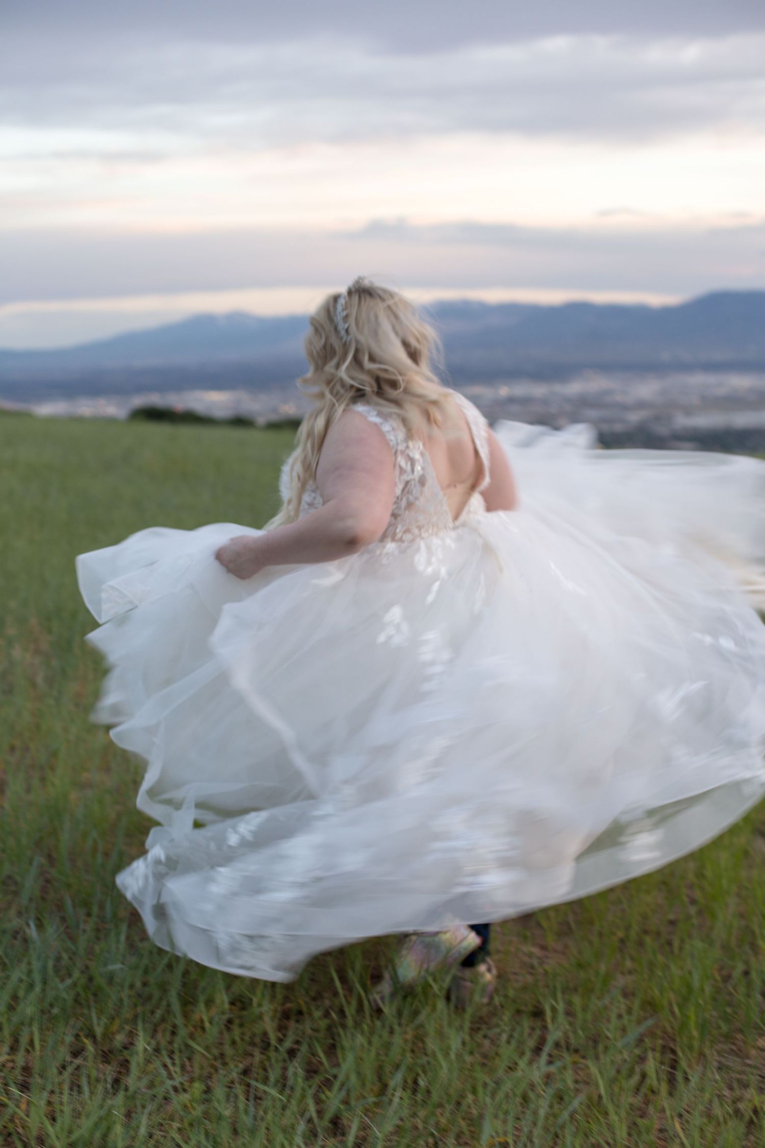 A billowing white wedding gown catches the wind on a scenic mountain overlook.