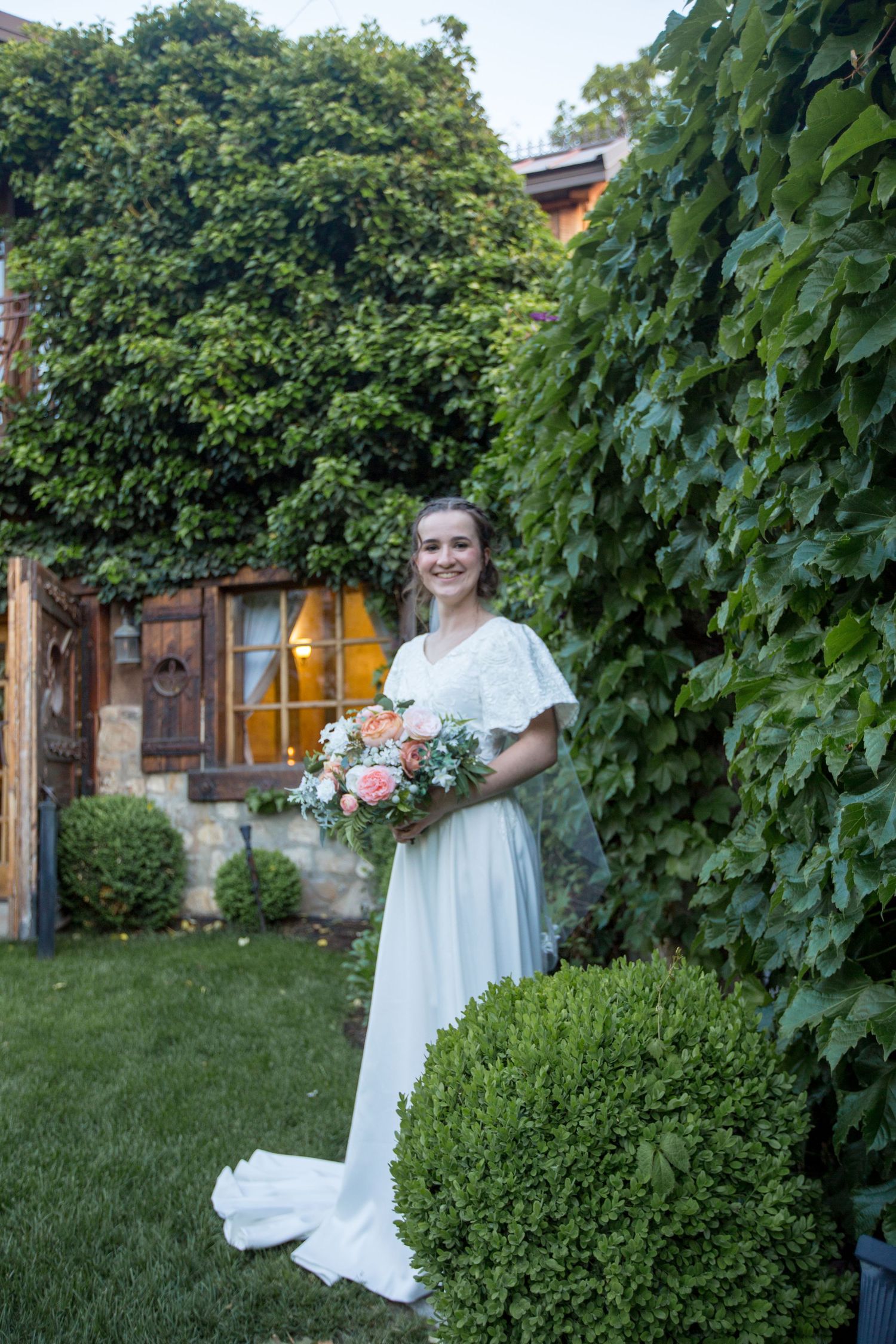 Garden wedding scene with boxwood shrubs and climbing vines creating a natural backdrop.