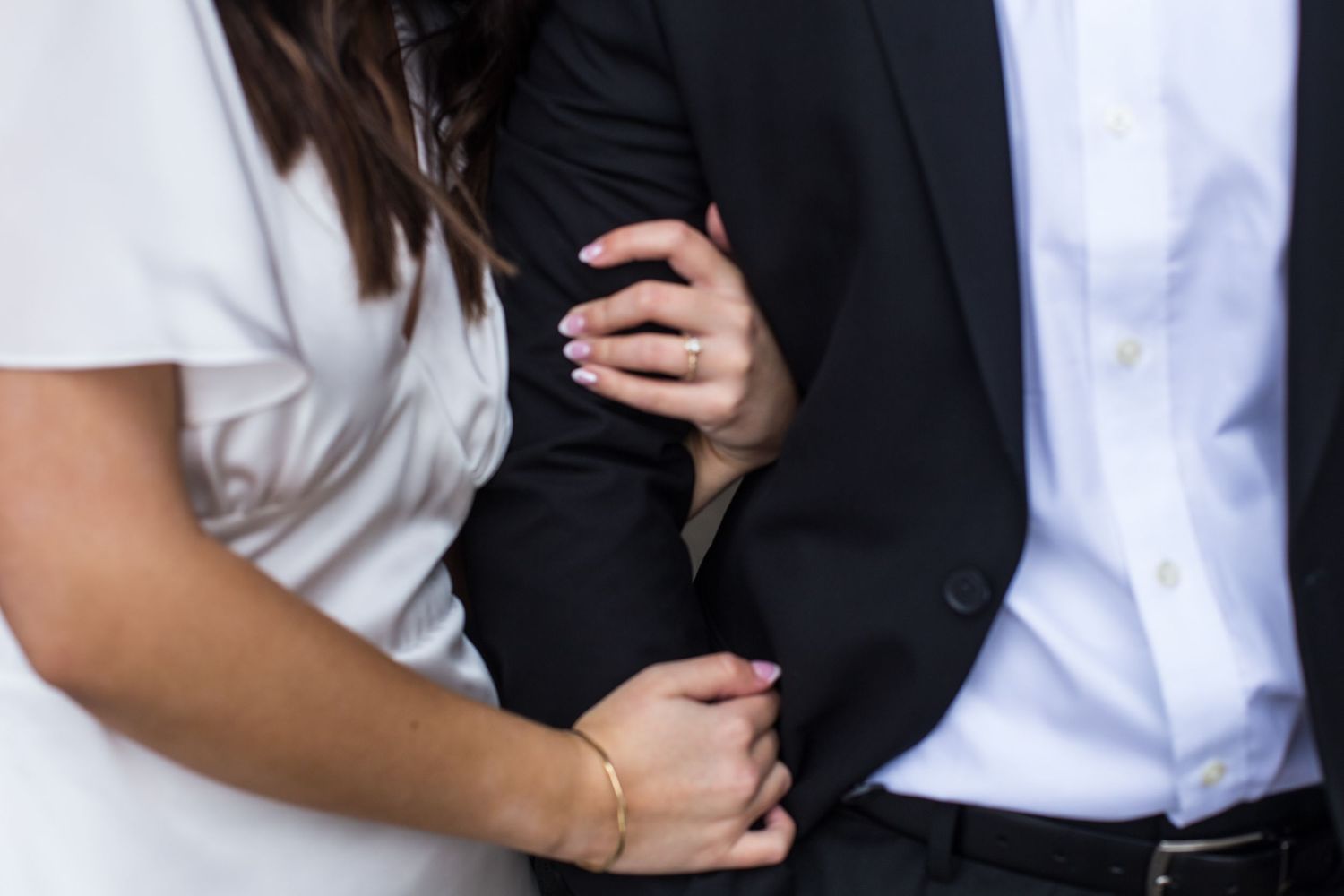 A couple shares a tender moment in formal black and white attire.