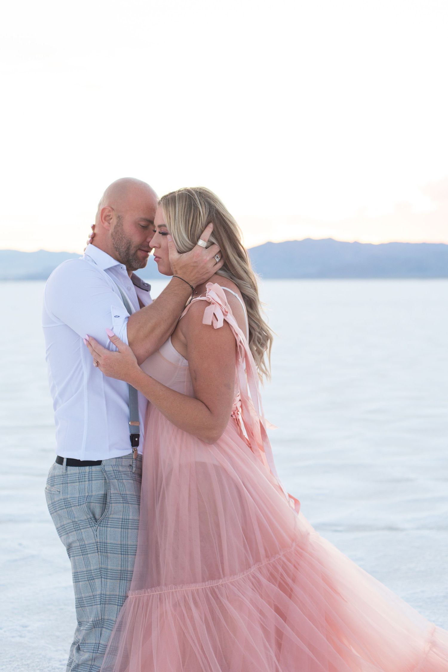 Flowing pink gown creates dreamy scene during beach portrait session.