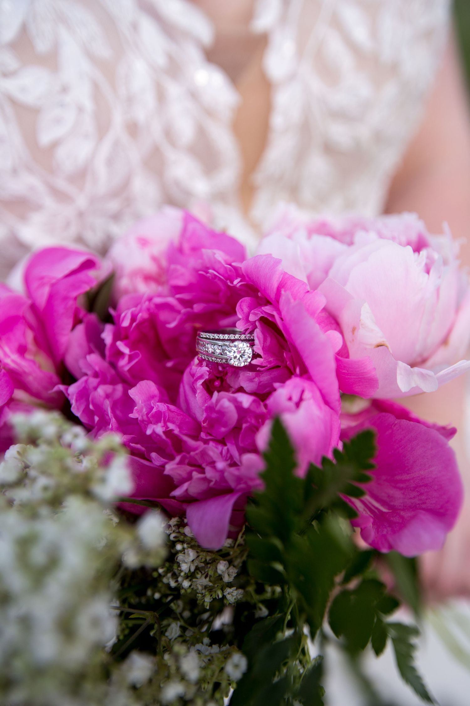 Close-up of pink peonies with a diamond ring nestled among the petals.