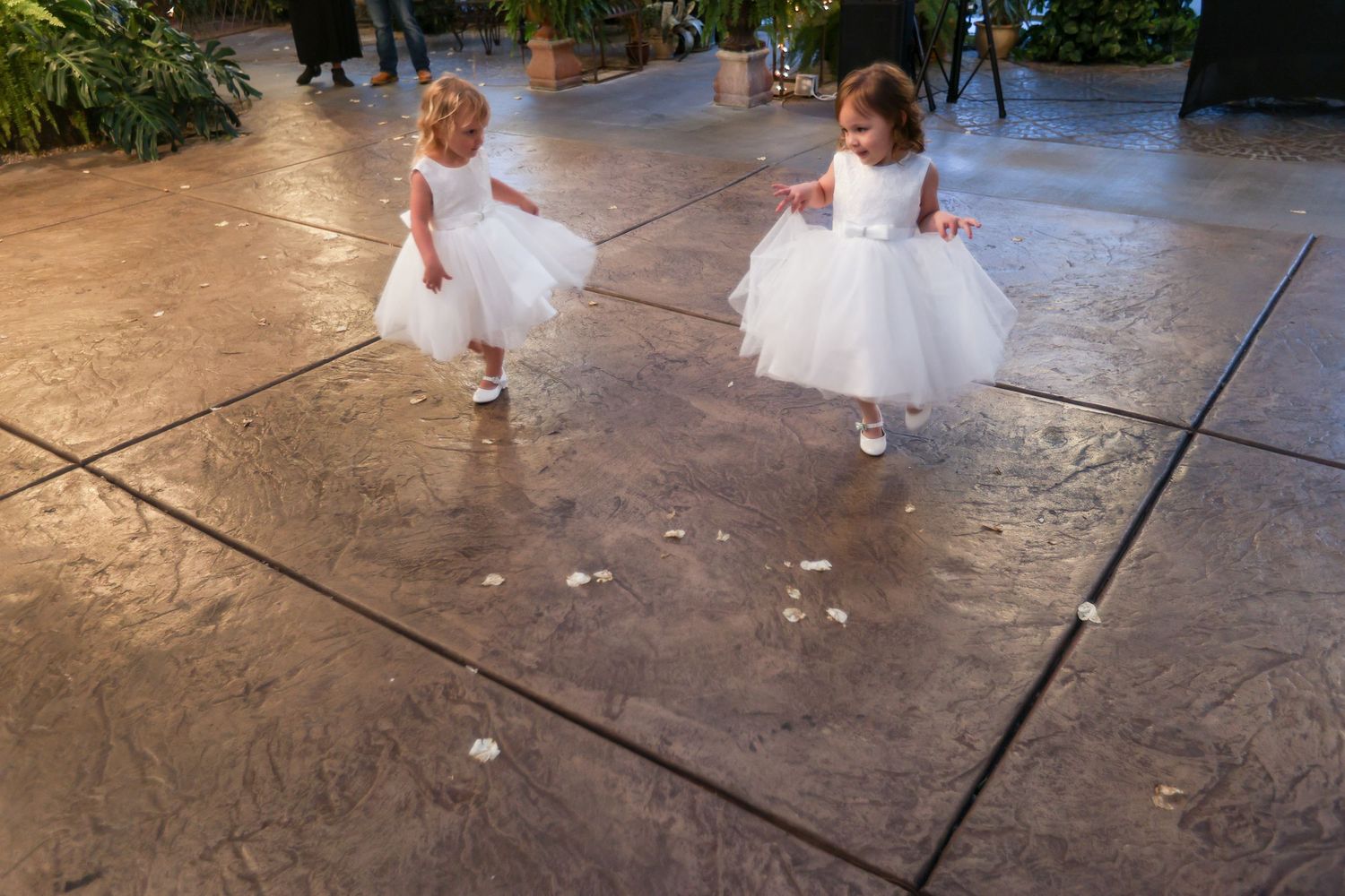 Young attendants in white dresses twirl and dance on a textured floor.