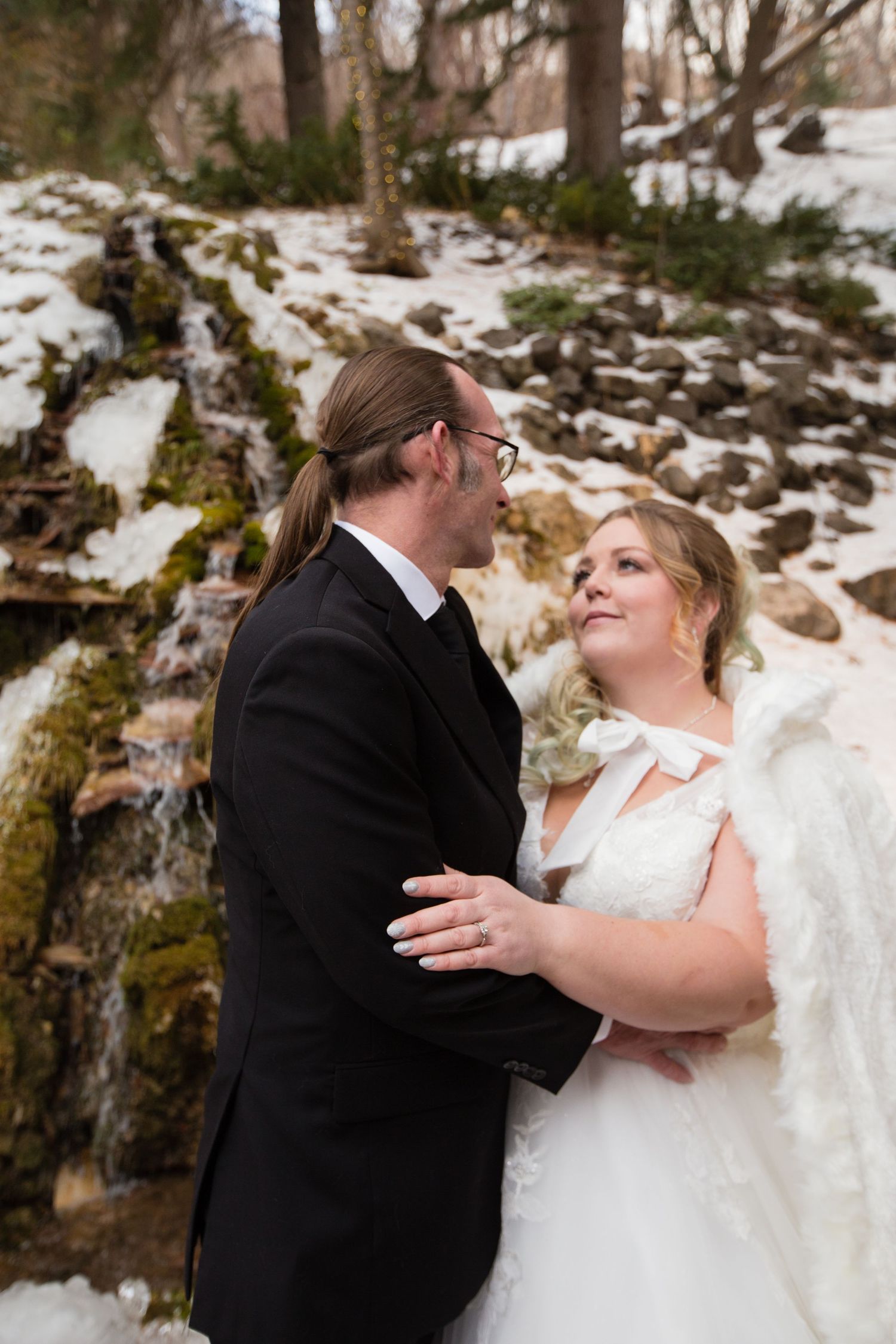 Candid wedding photos capturing sweet moments between newlyweds in a winter forest setting.