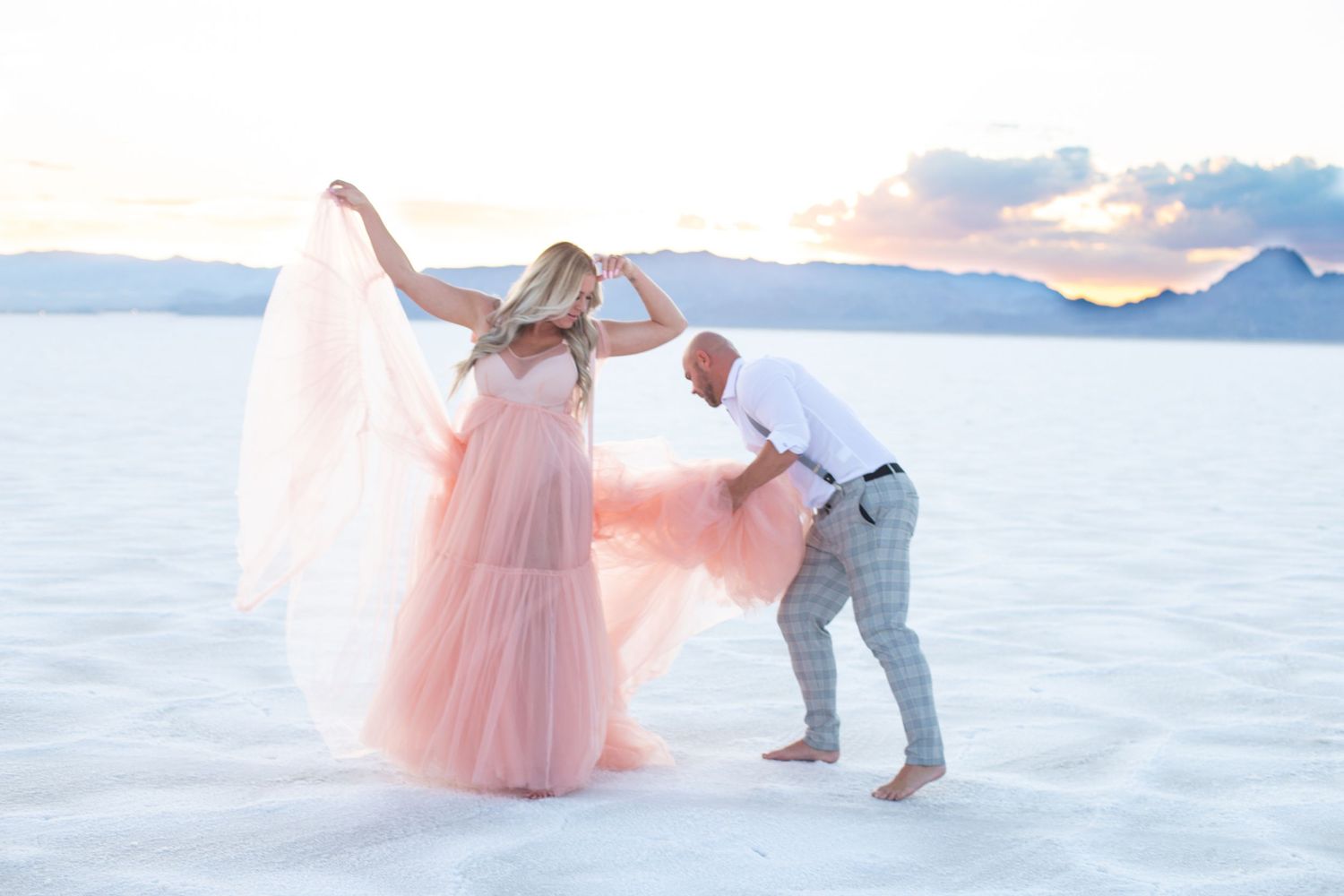 A ethereal wedding photo with flowing pink dress against white salt flats.