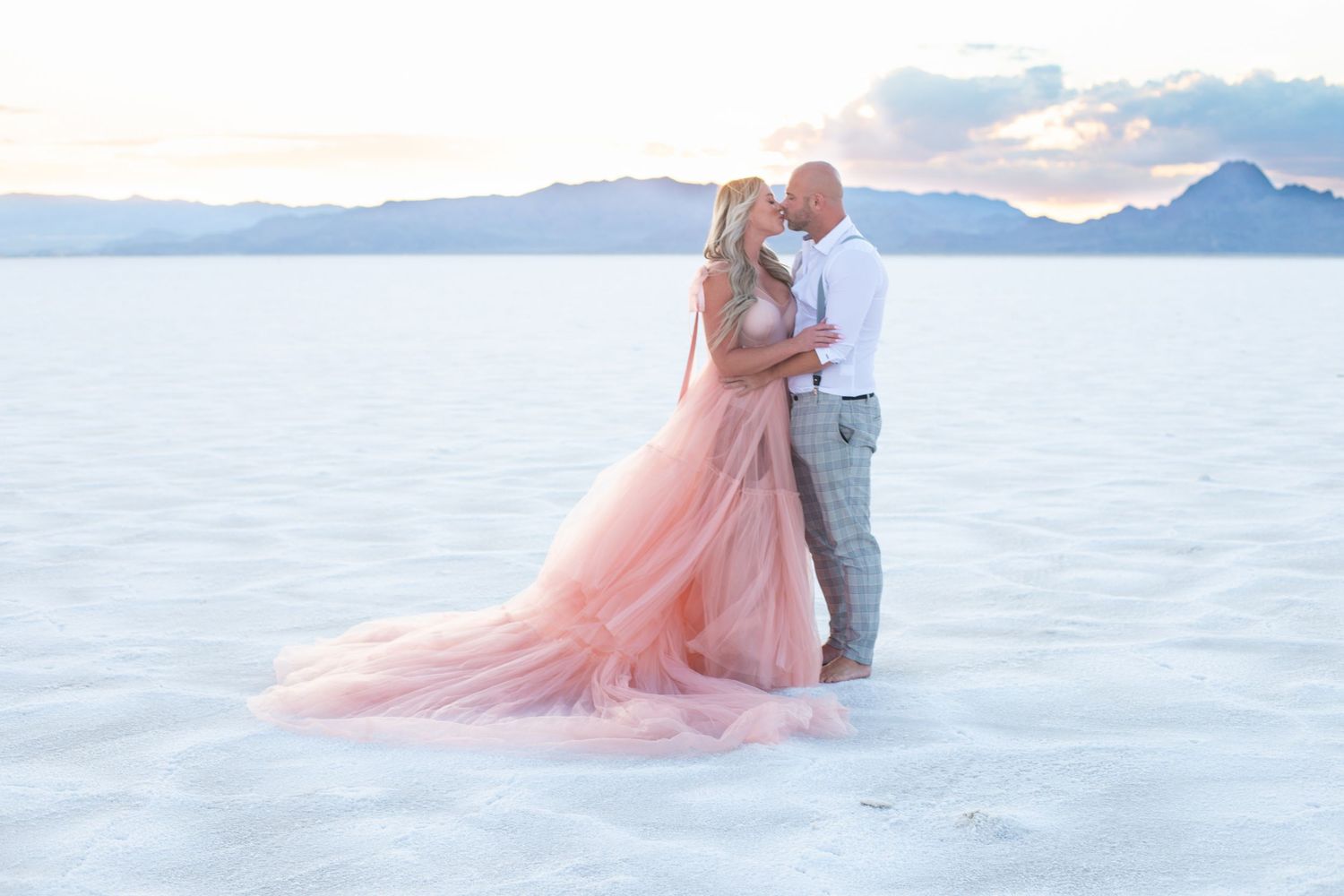 A romantic couple's portrait session on salt flats with mountains in the background.