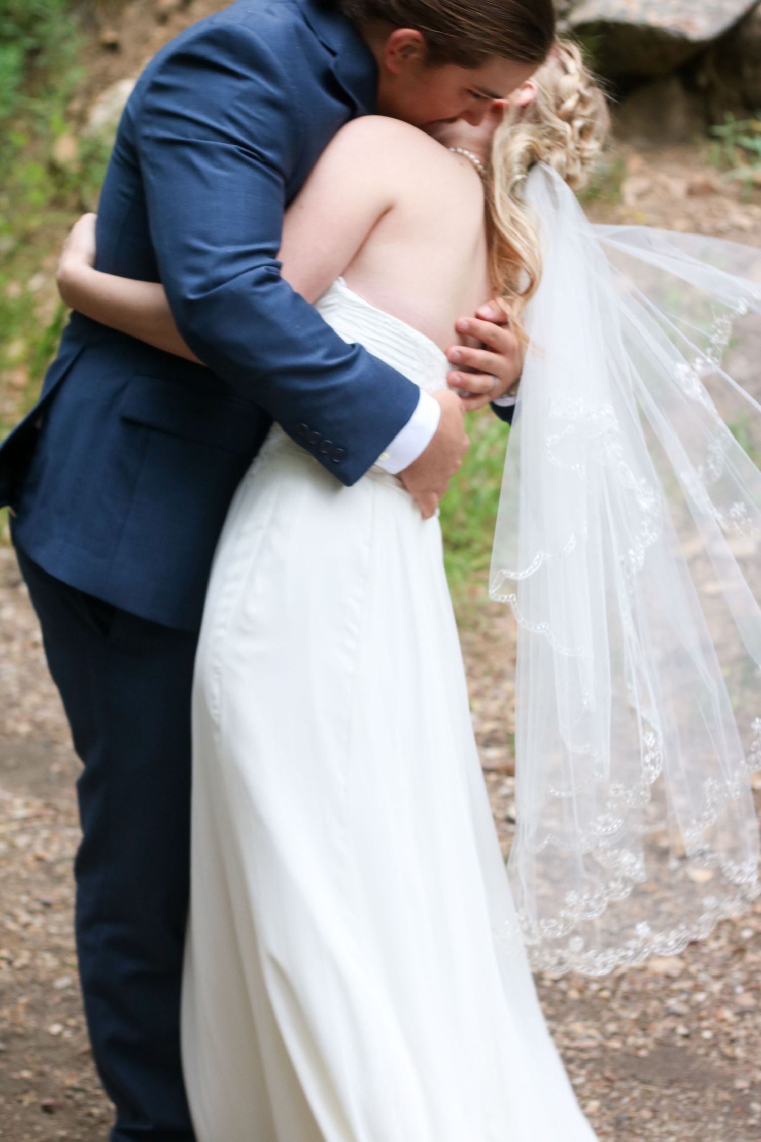 Romantic wedding portraits on nature path showing intricate lace veil details.