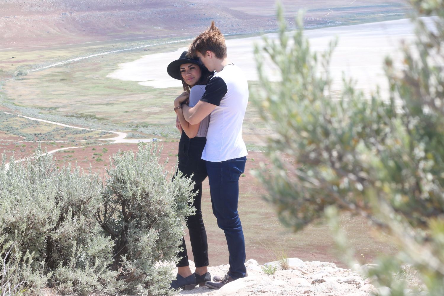 A romantic moment between two people on a beach with desert vegetation.