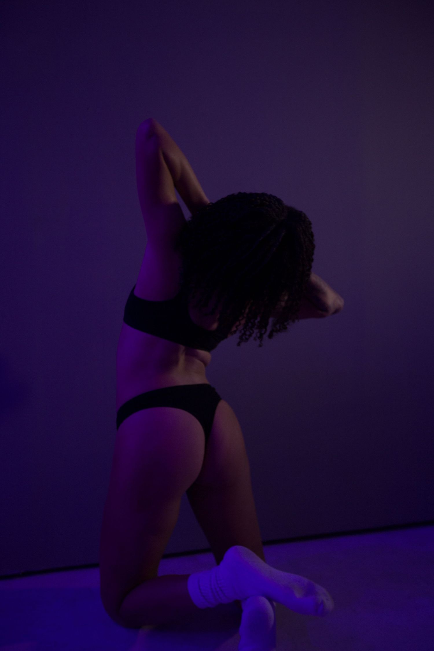 Artistic boudoir silhouette under purple lighting.