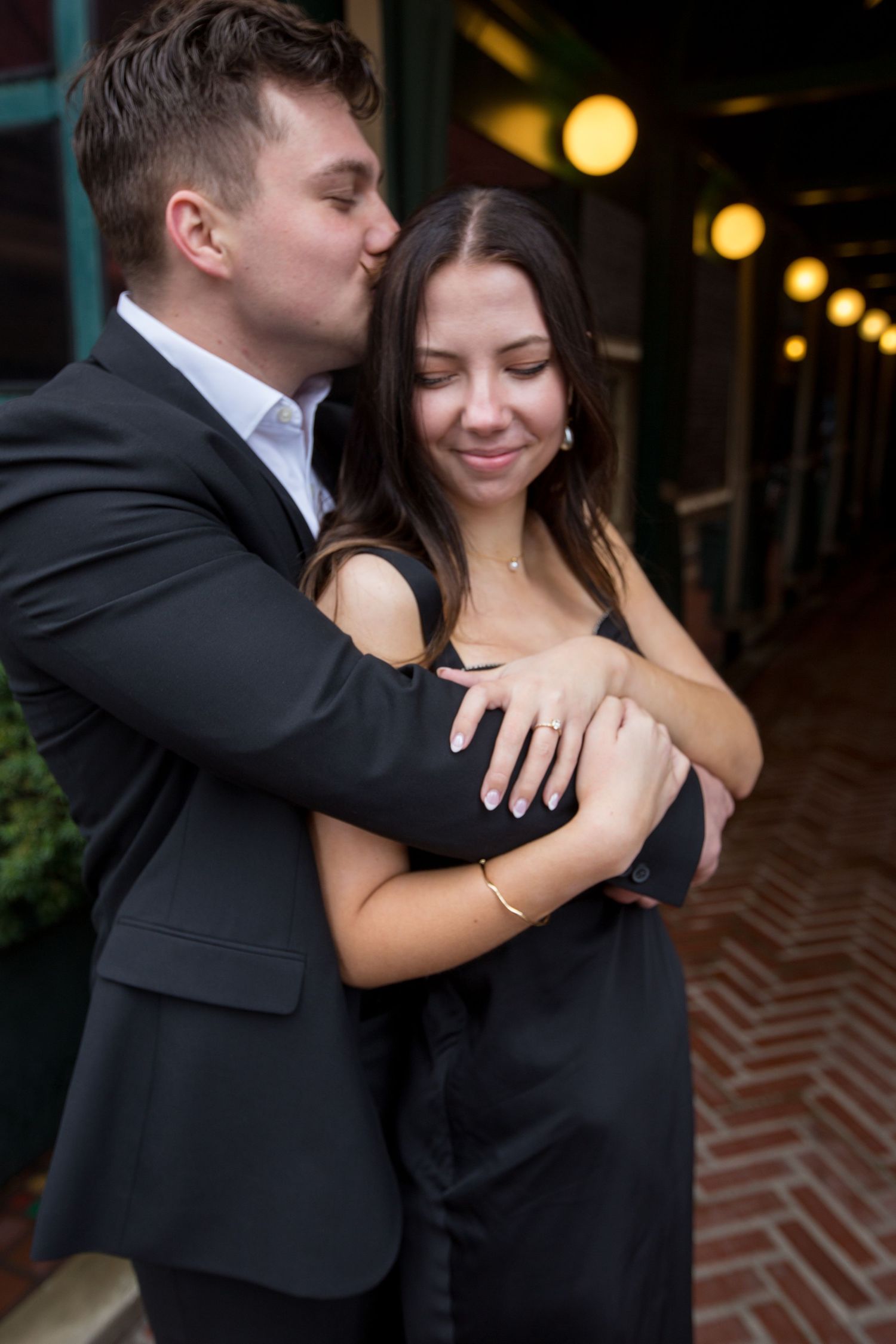 Intimate embrace between couple in black formal attire.