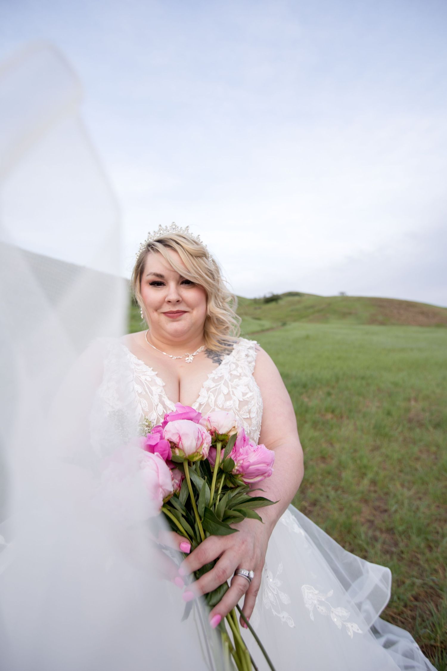 Dreamy outdoor bridal portrait featuring a white lace dress and pink peony bouquet.