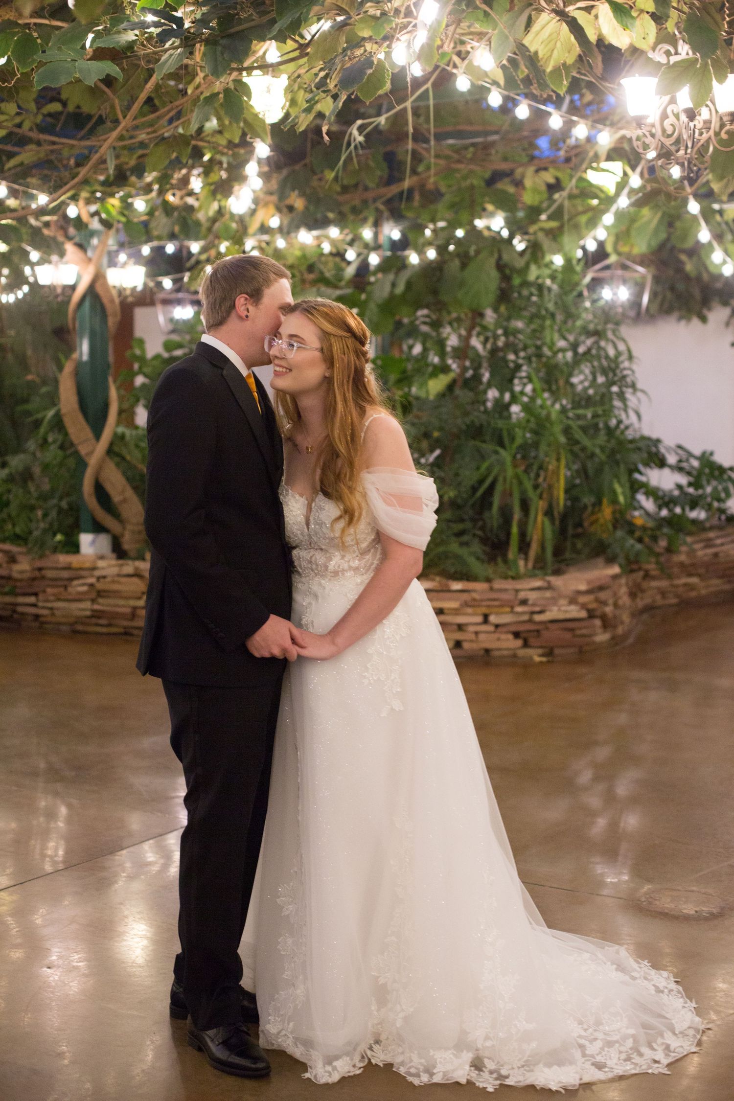 A romantic first dance moment under twinkling lights in a garden setting.