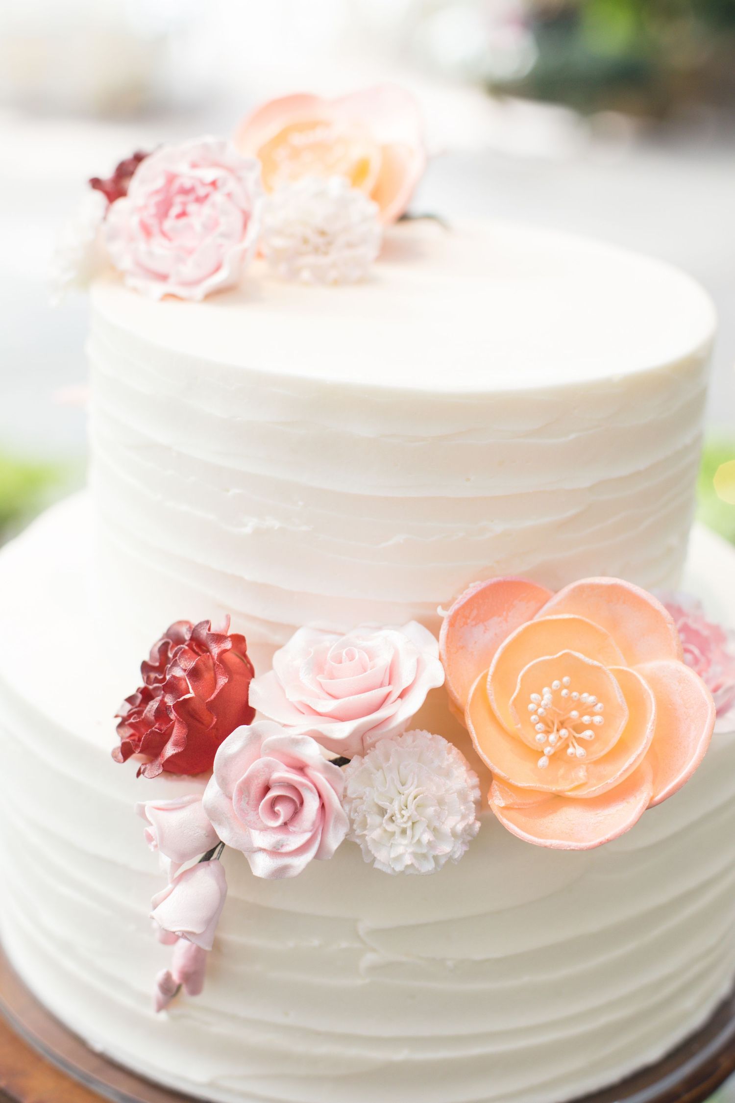 Elegant white wedding cake adorned with delicate pink and peach sugar flowers.