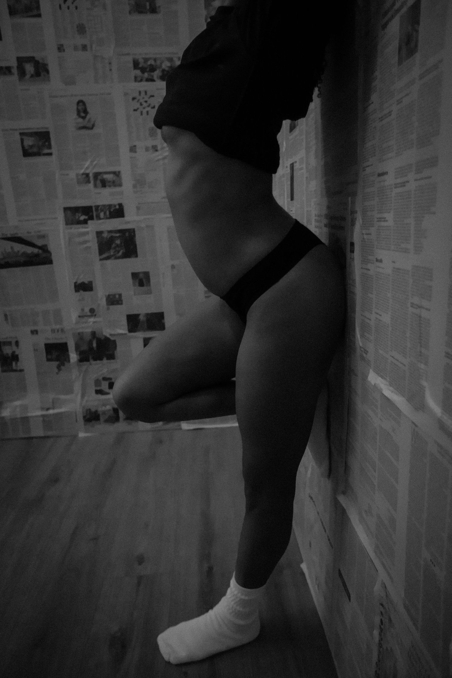Black and white photo series against newspaper wall showing artistic poses in moody lighting.