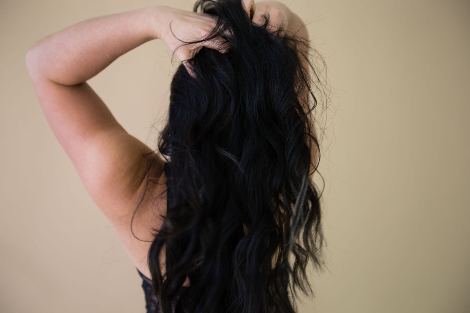 Long dark hair cascades down back in artistic portrait.