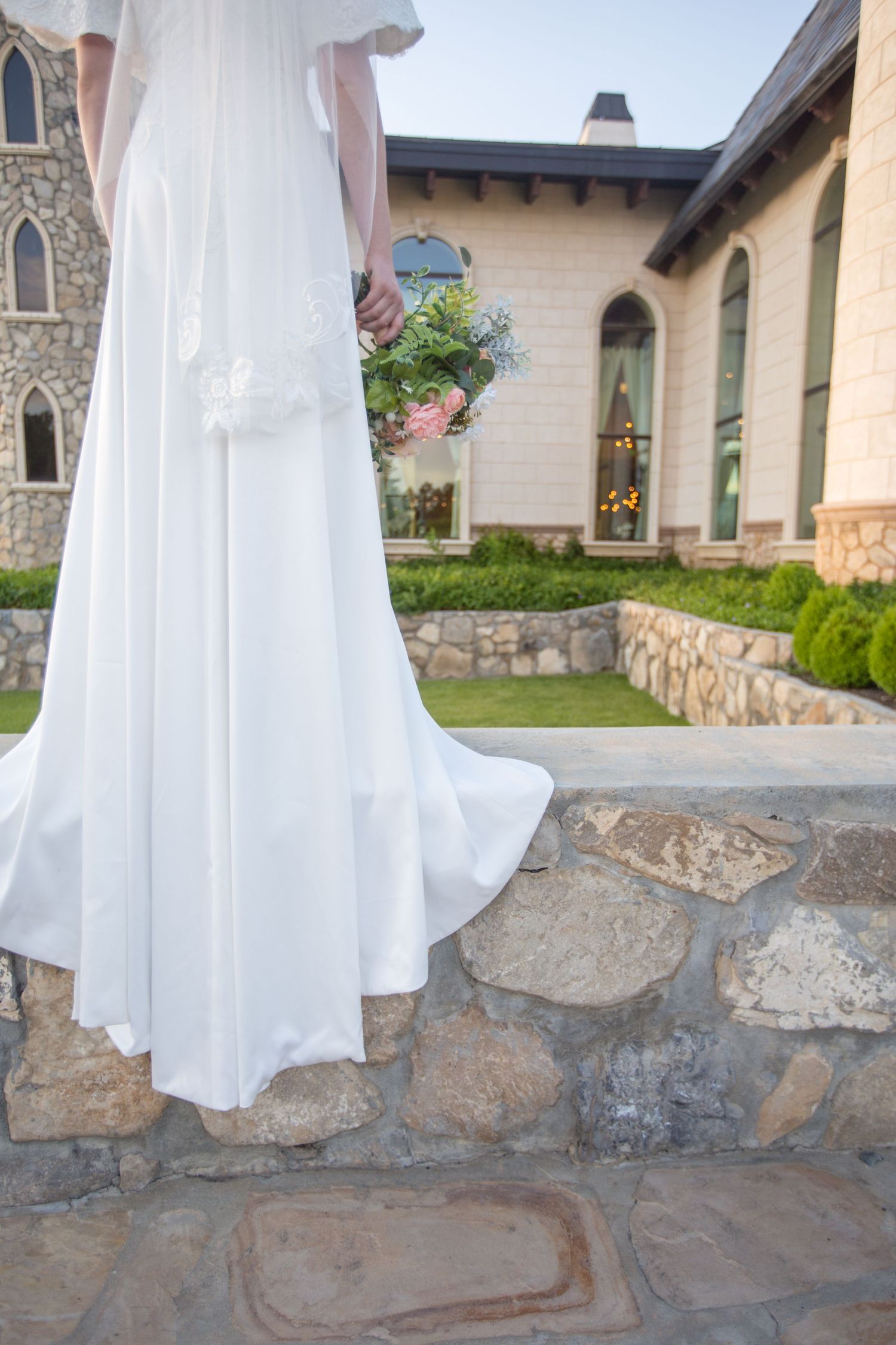 White dress flowing against stone wall architecture.