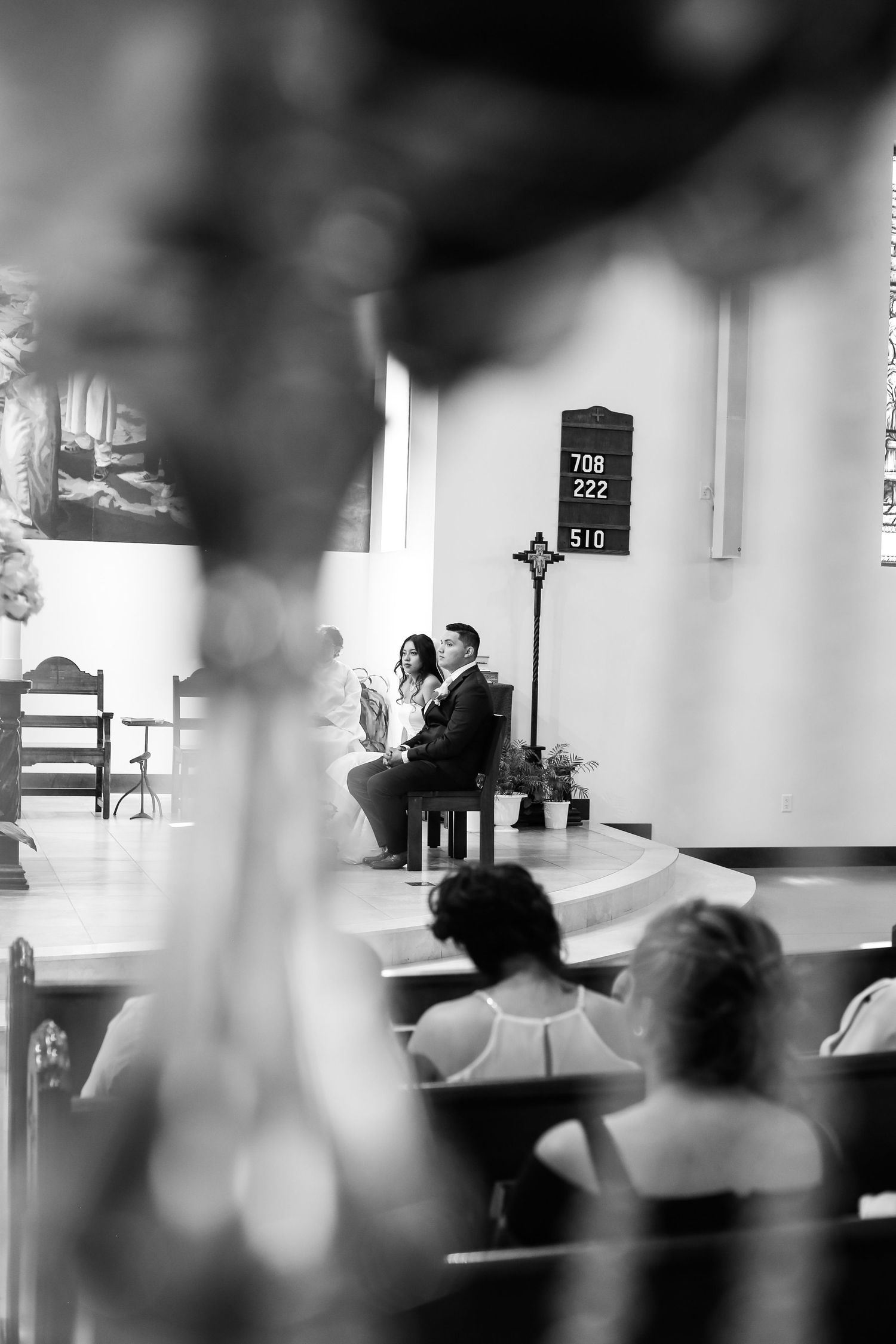 Black and white image of people sitting in a church pew during a religious service.