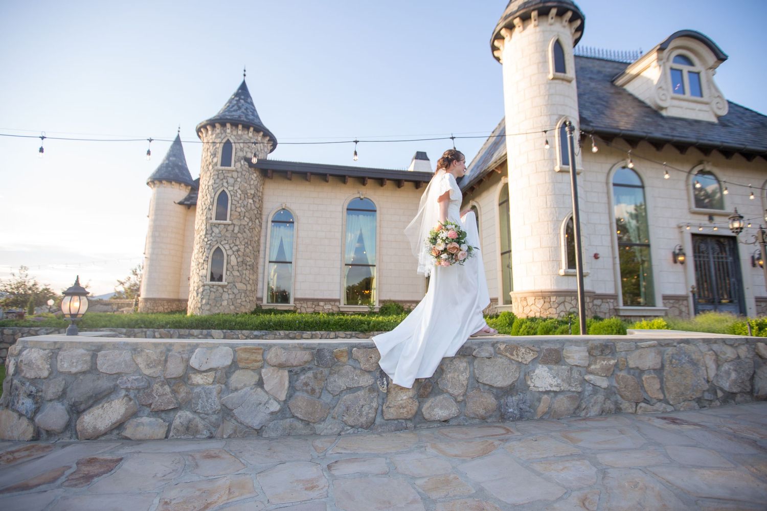 Castle-style wedding venue with stone walls and turrets in evening light.