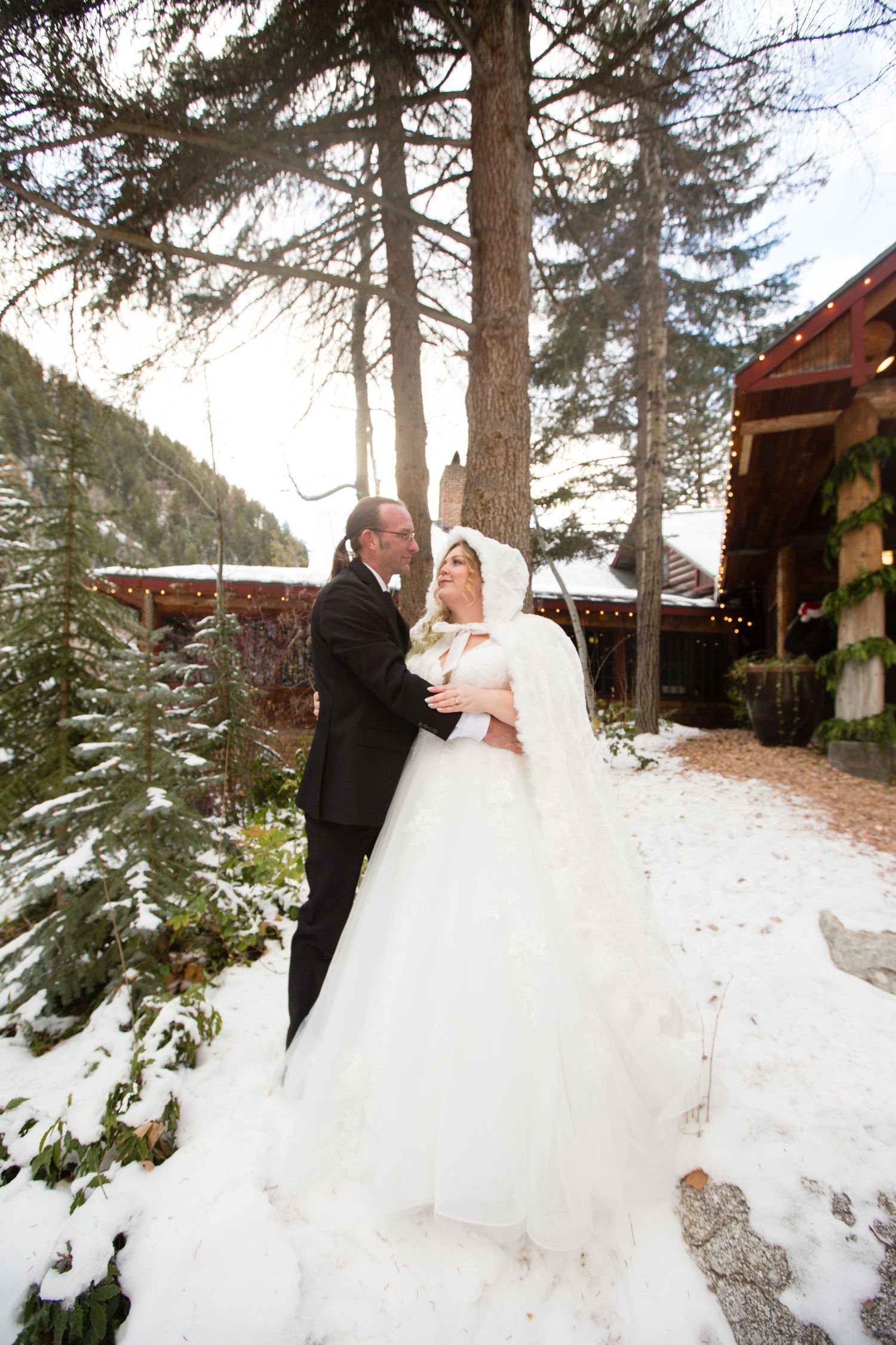 A winter wedding moment captured against a backdrop of tall pine trees and mountain scenery.