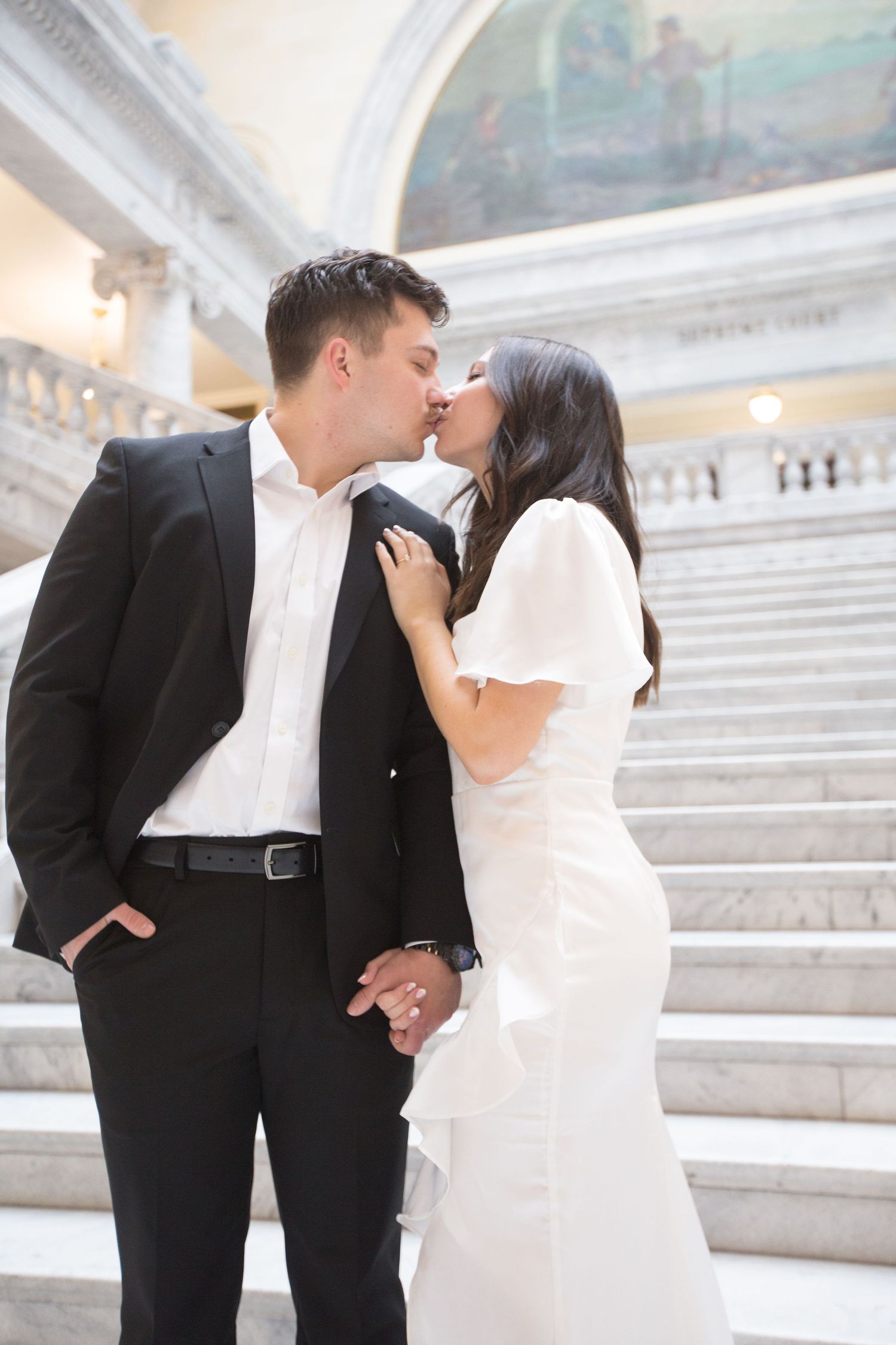 A tender moment captured against the backdrop of an ornate marble staircase.