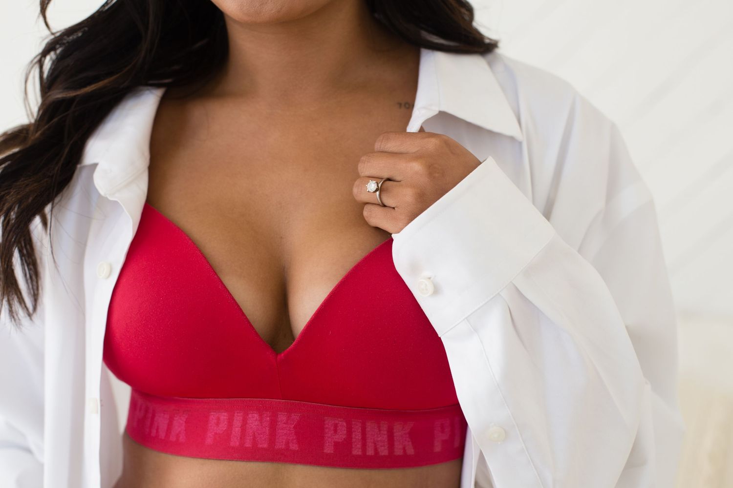 Woman wearing a red Victoria's Secret PINK wireless bra with an open white button-down shirt.