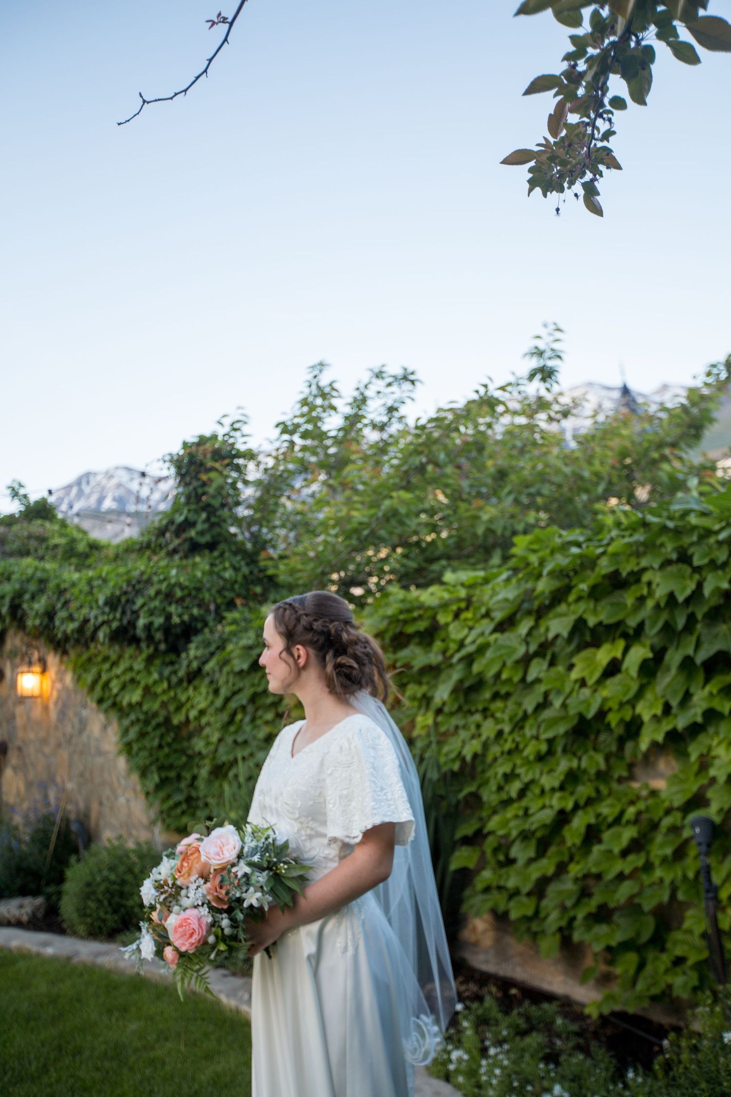 A garden wedding scene with mountain views and ivy-covered walls in the background.