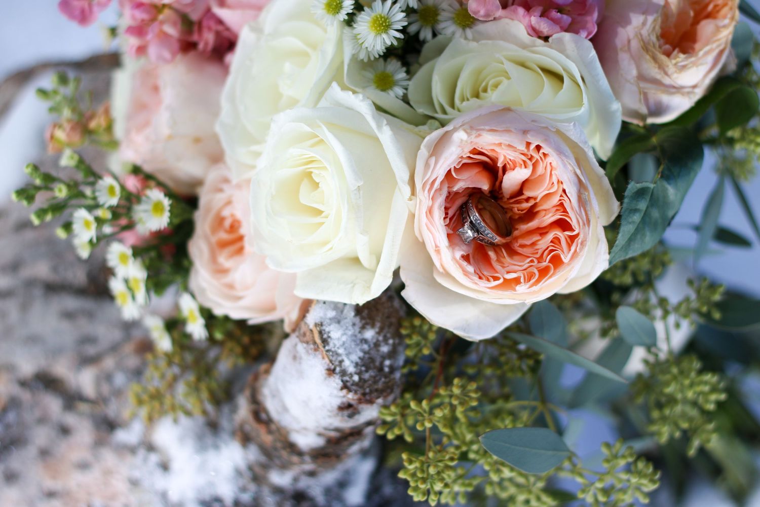 Elegant bouquet of white and peach garden roses with delicate greenery against a textured background.
