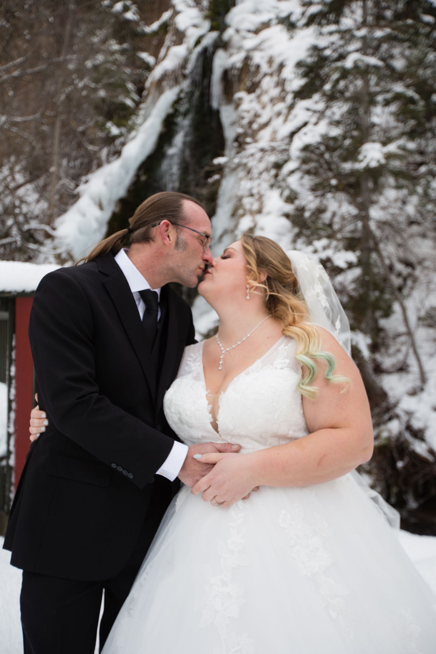 Romantic winter wedding portraits with snow-covered cliffs in background.