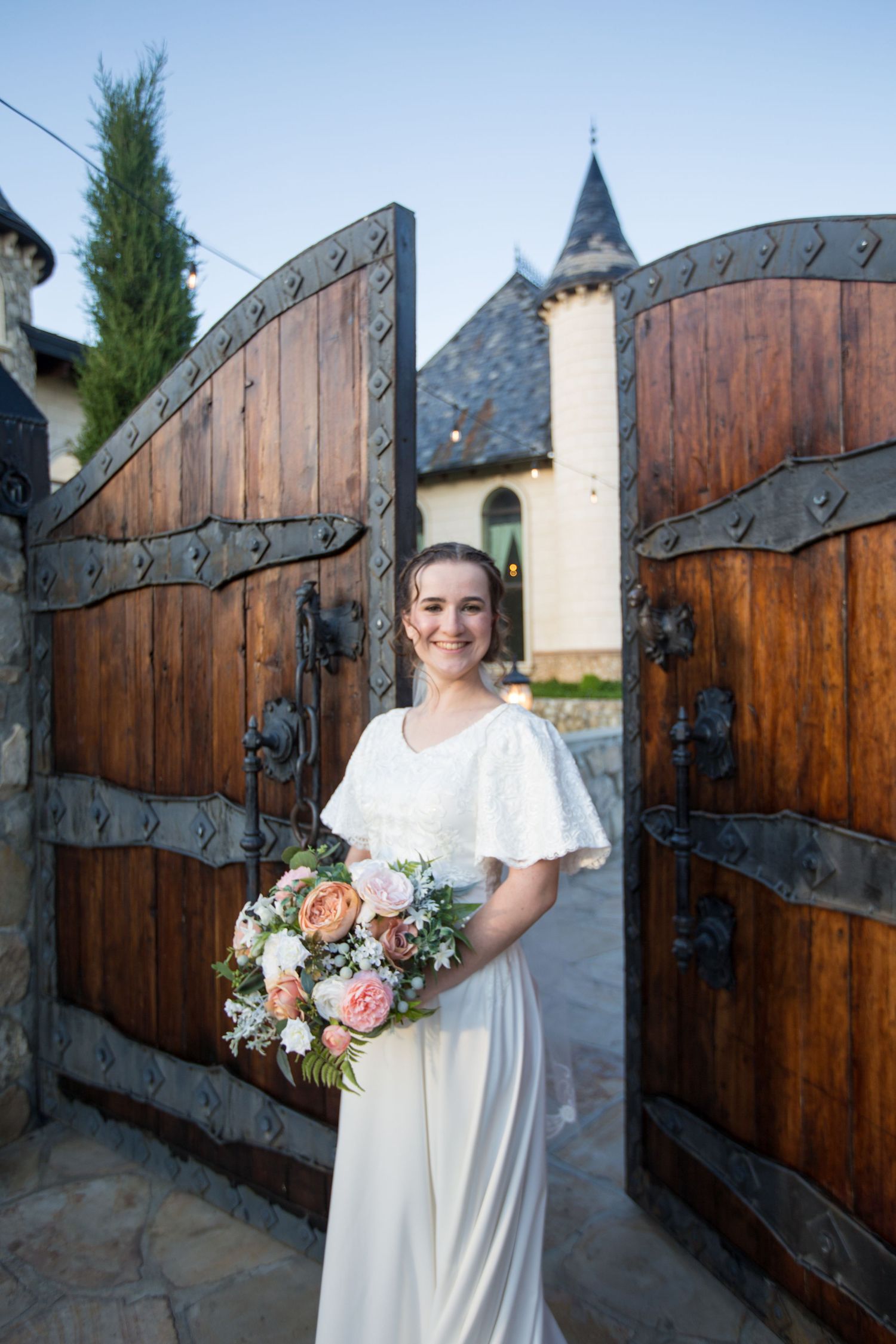 Ornate wooden gates and stone walls frame bridal portrait.