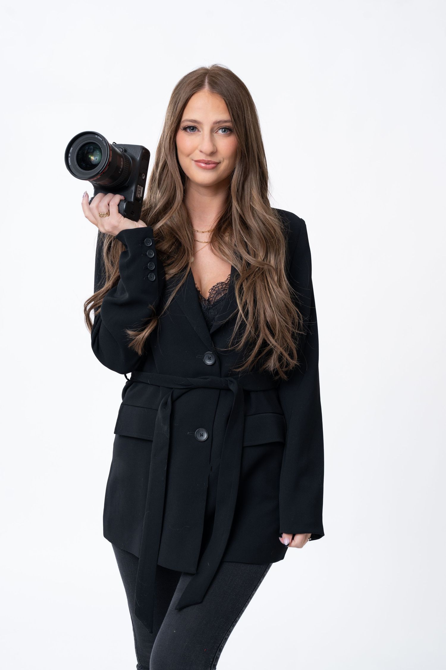 Professional photographer demonstrating different camera poses in black business attire.