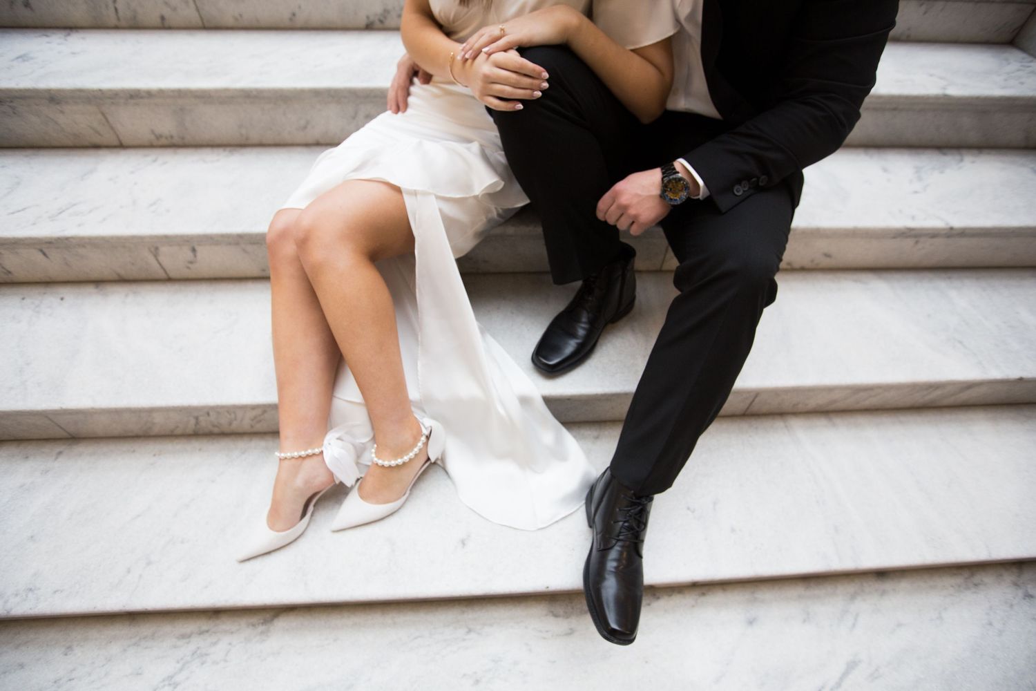 Close-up of formal attire and shoes on white marble steps during a special occasion.