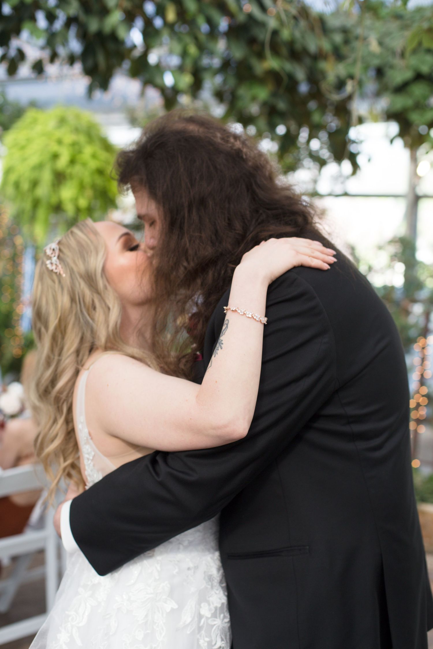 Romantic wedding moment captured in a greenhouse setting with natural lighting.