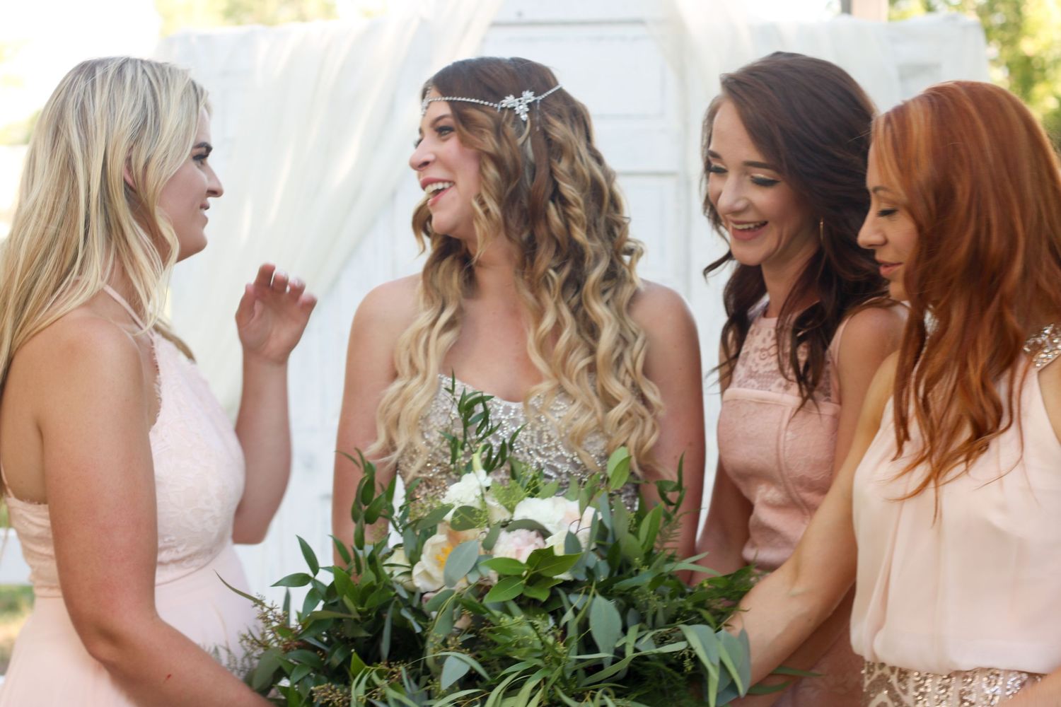 Group photo of bridesmaids holding bouquets and wearing light colored dresses.