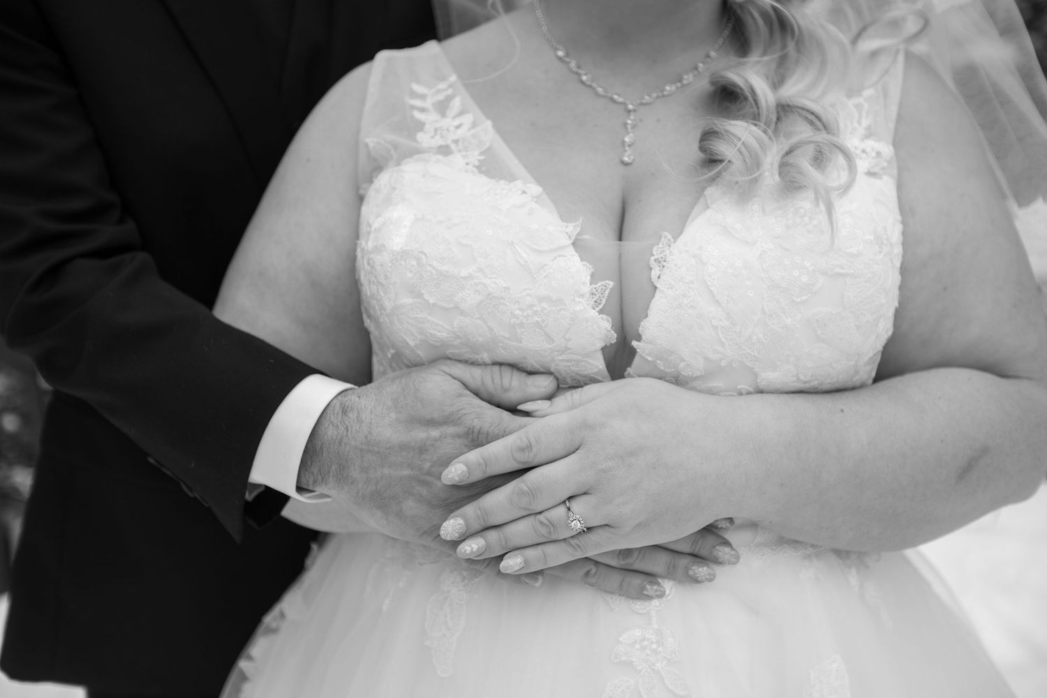 Detail shot of white lace wedding dress bodice with delicate jewelry.
