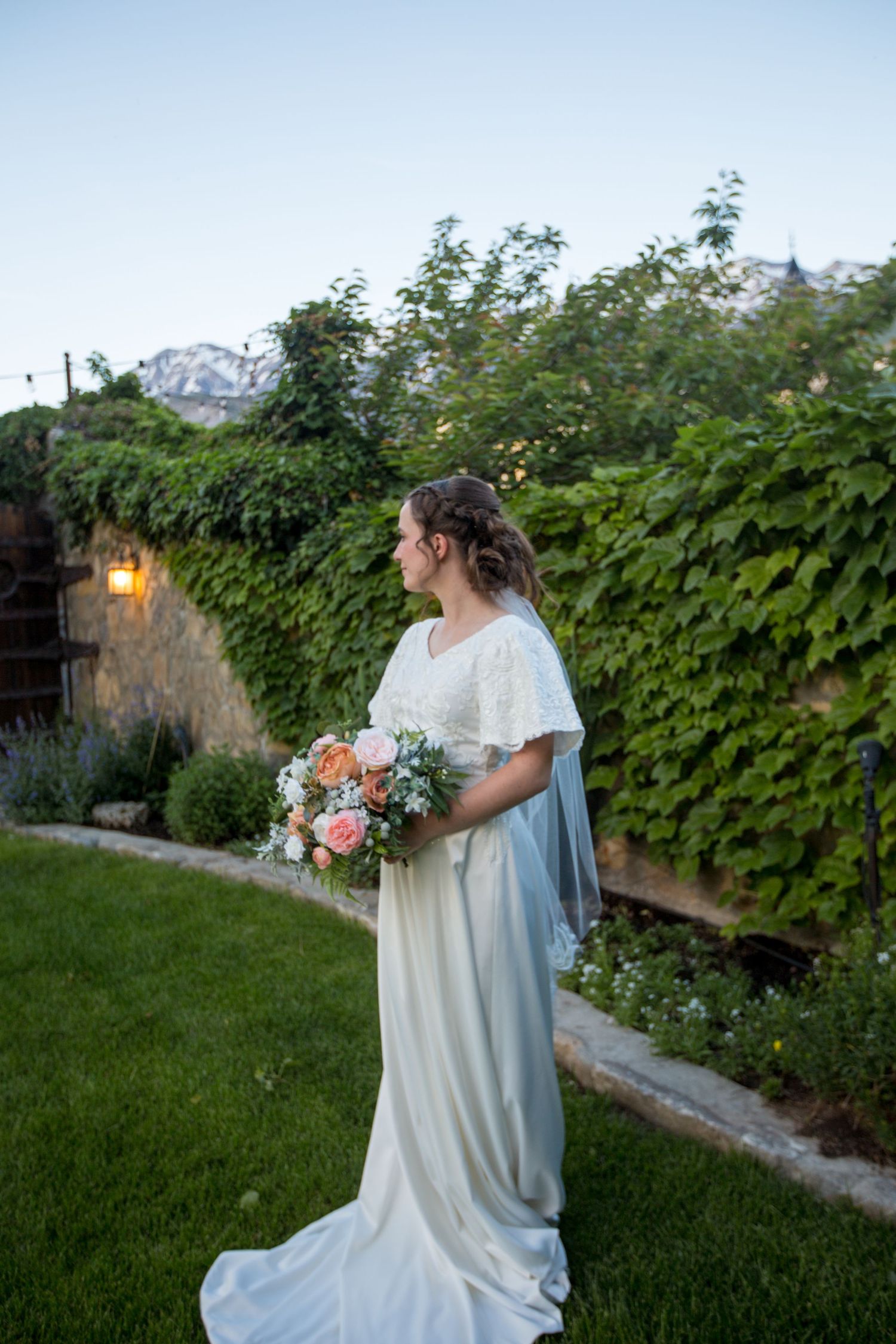 A romantic bridal portrait in a garden setting with mountains visible in the distance.