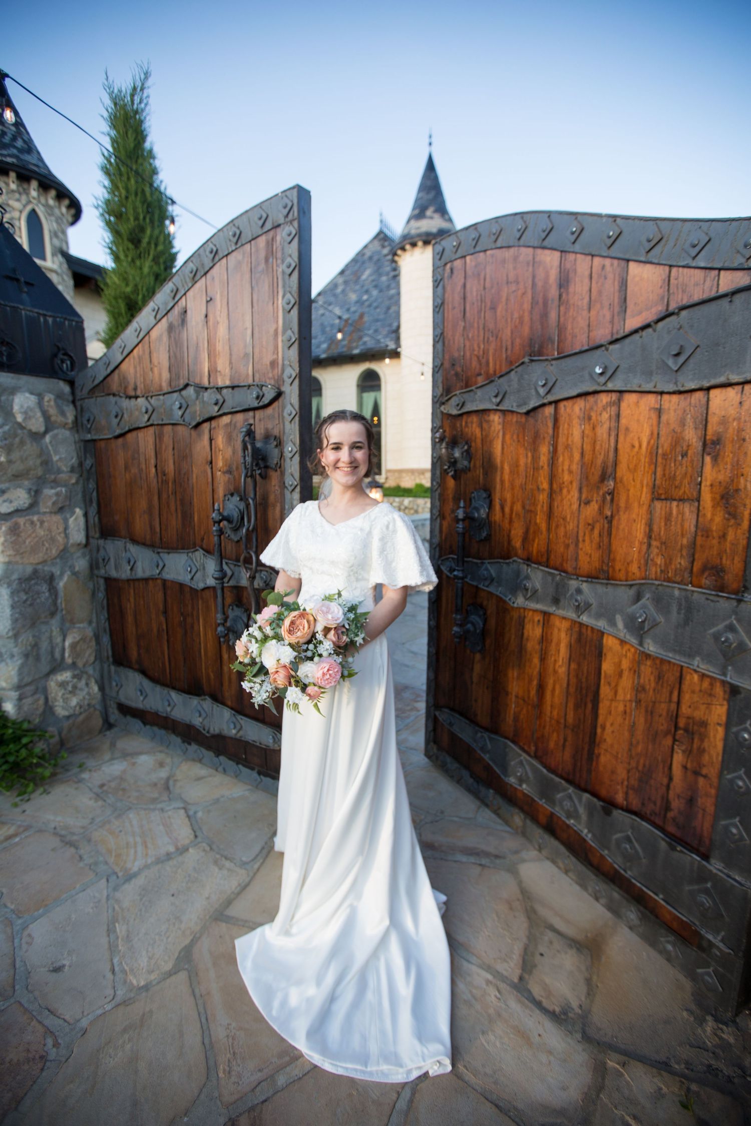 Rustic wooden gate entrance with stone walls and castle architecture.