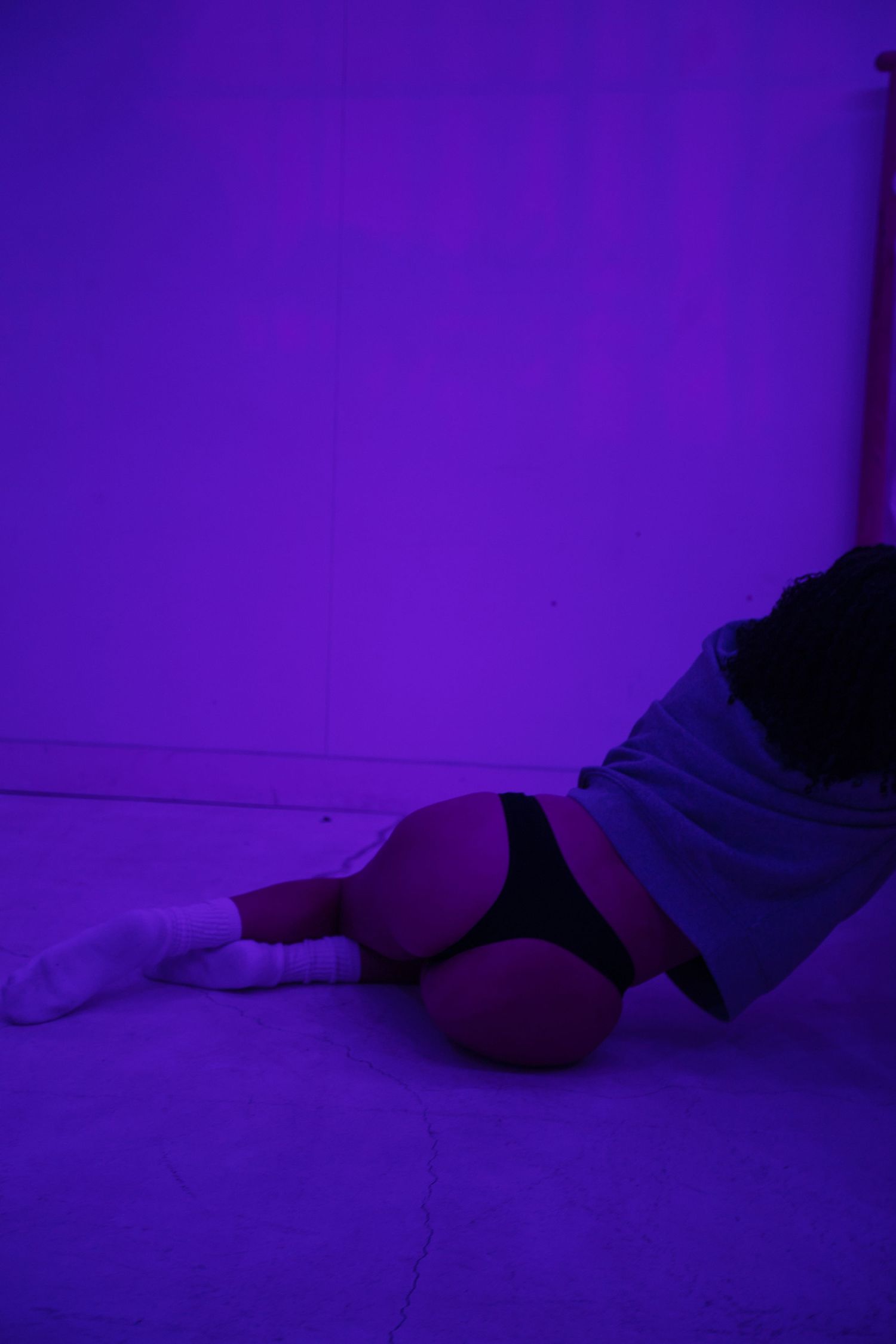 Person lying on ground in dramatic purple-lit environment.