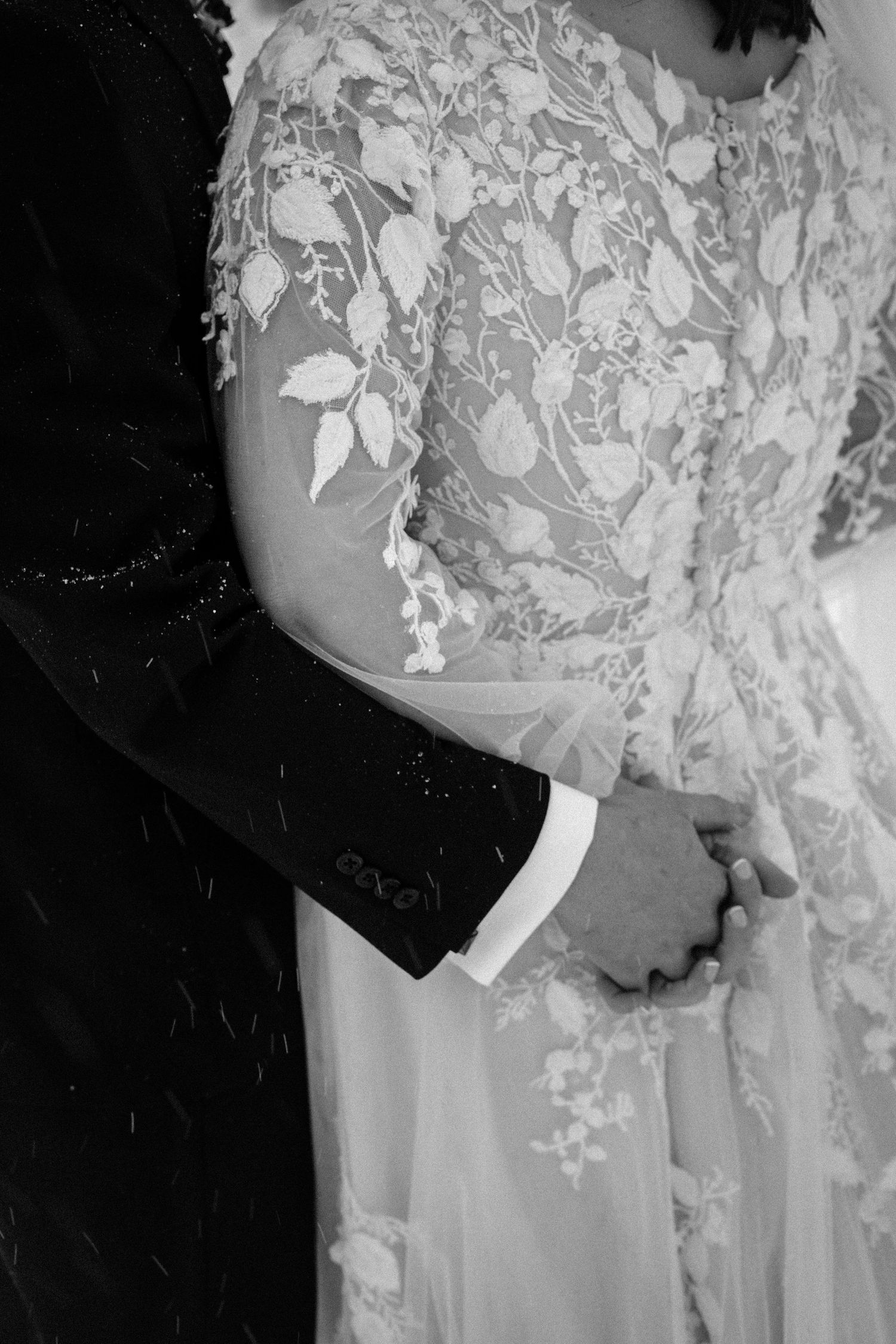 Close-up details of delicate white lace and floral appliques on a wedding dress.