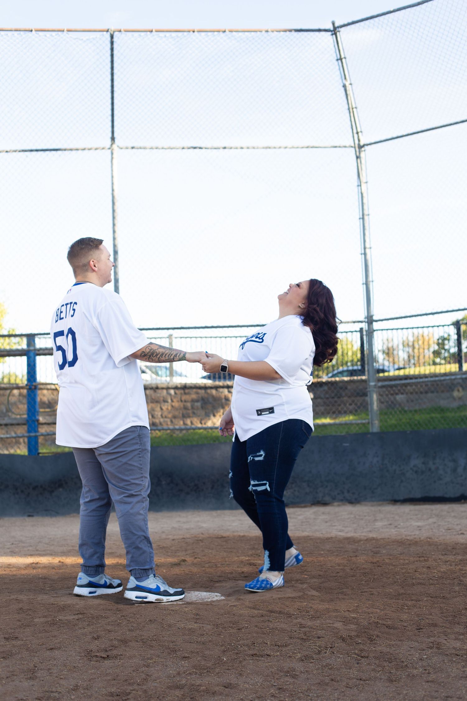 A couple in matching white jerseys plays together on a baseball field.
