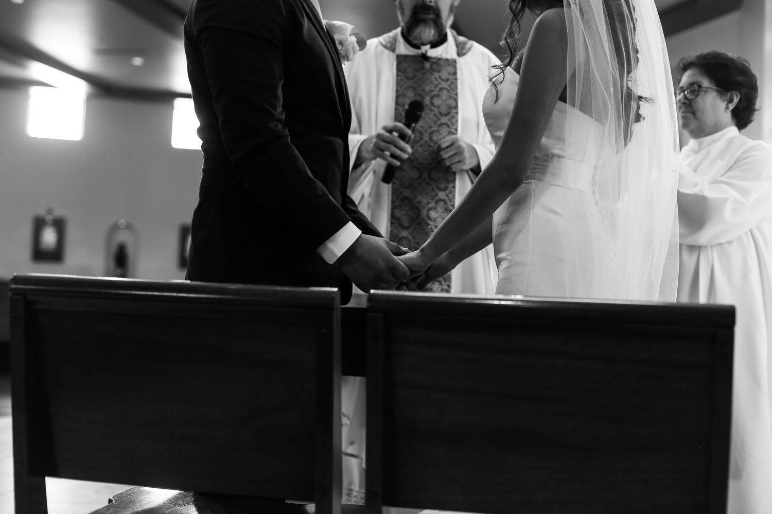 A black and white photo shows a group of people gathered in a dimly lit room during what appears to be a wedding ceremony.