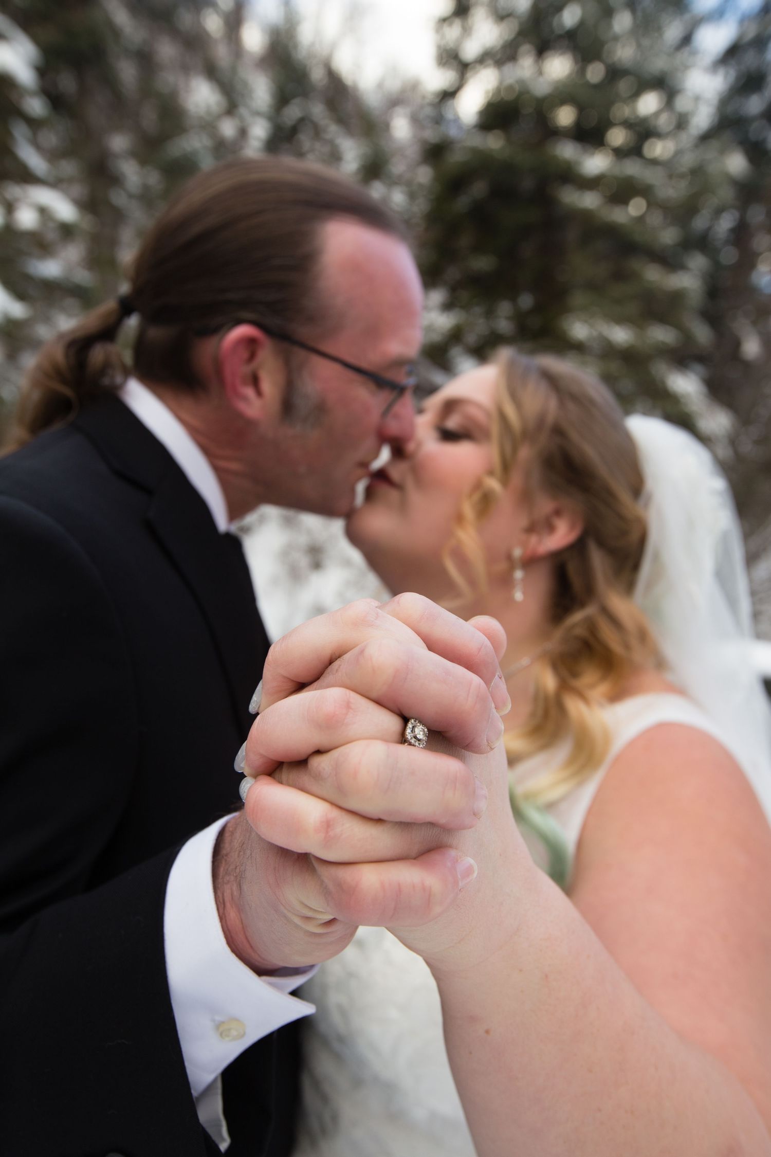 A romantic winter wedding moment captured in a close-up shot against a snowy backdrop.