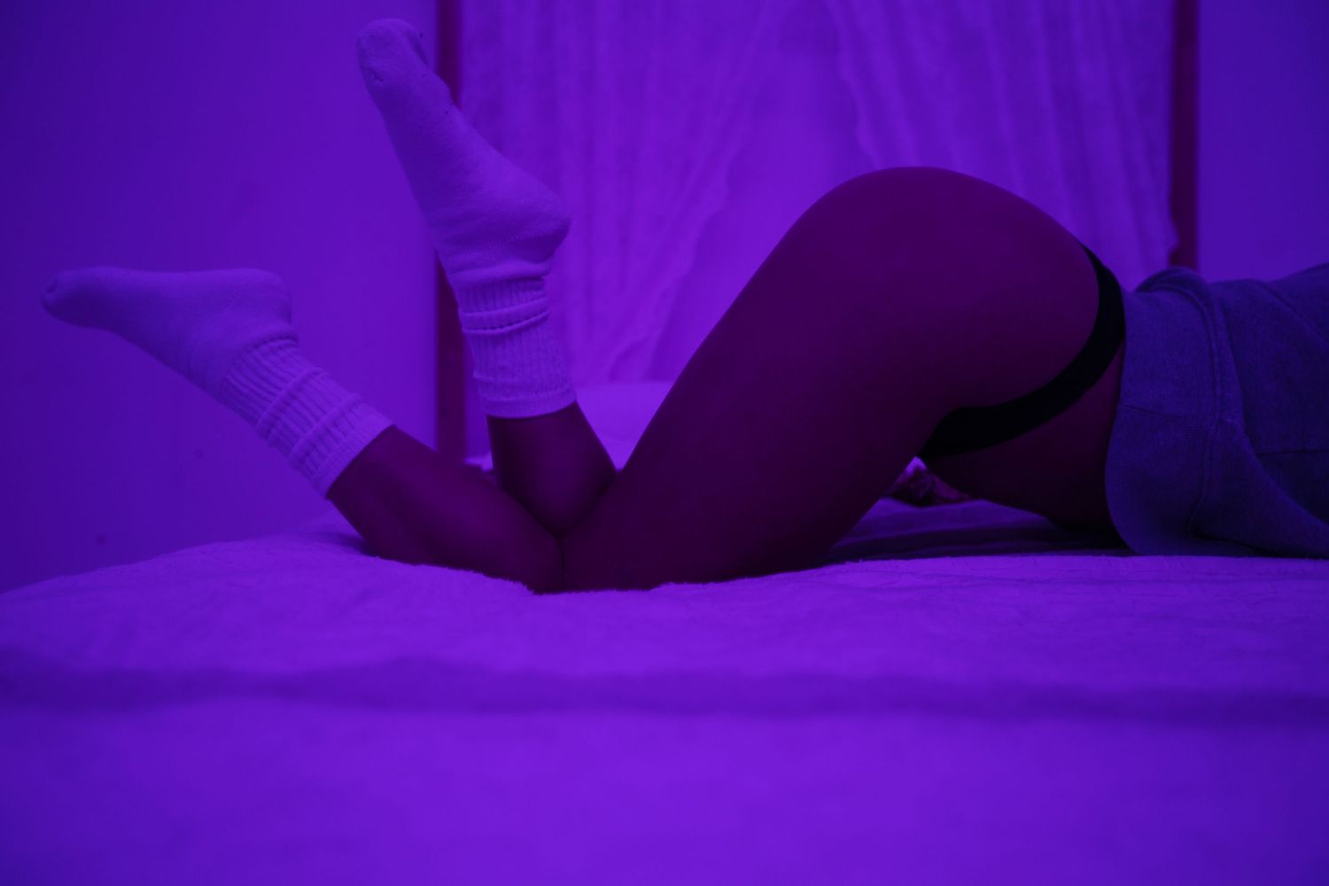 Silhouetted figure reclining on floor under purple lighting.
