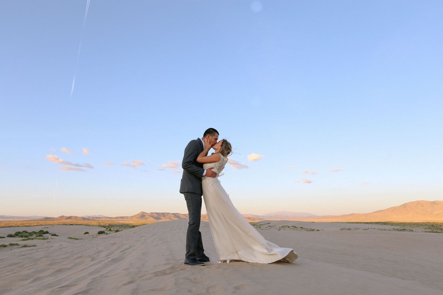 Wedding photos taken in sand dunes during sunset with dramatic desert landscape.