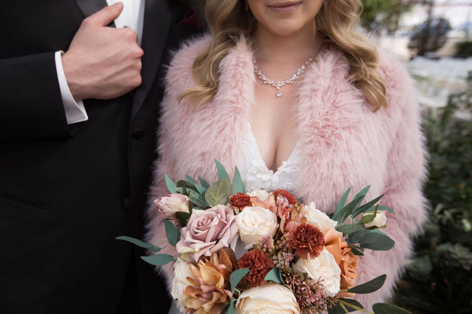 Wedding bouquet with pink and white flowers held against a pink fur coat.