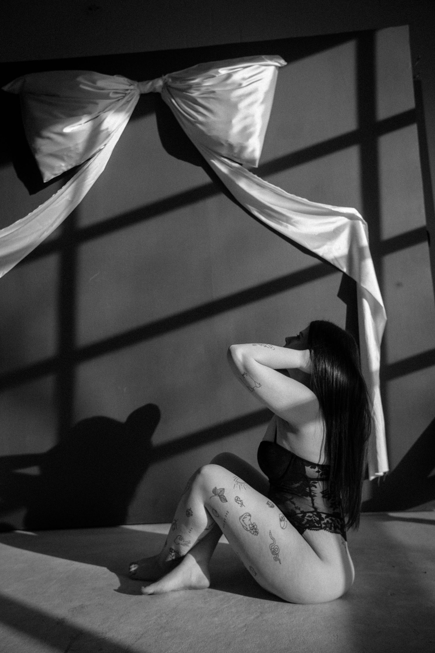 Black and white artistic photo with dramatic lighting and fabric elements.