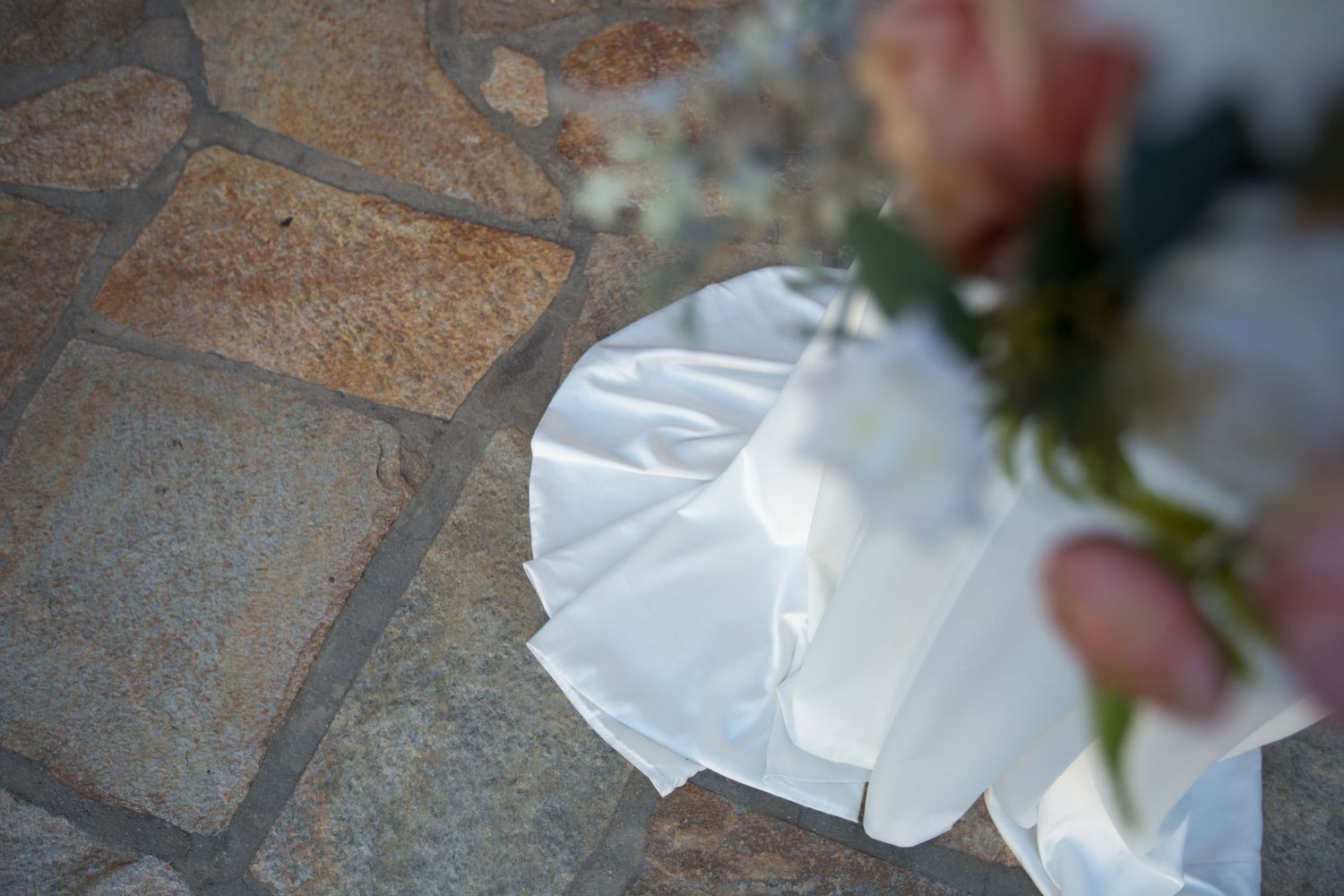 White dress flowing over stone pavers in an outdoor setting.