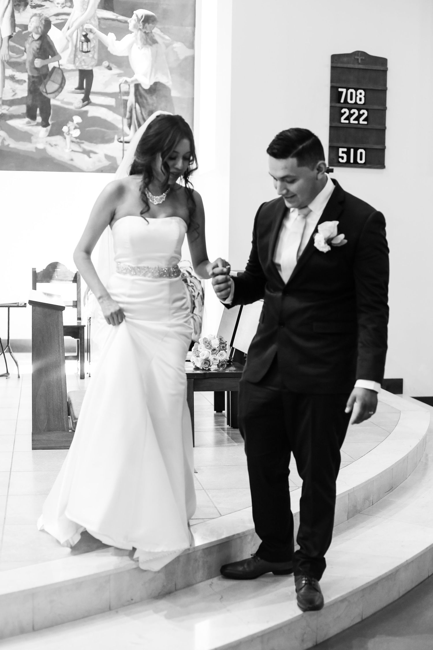 A bride and groom share a tender moment on a staircase during their wedding day, captured in black and white.