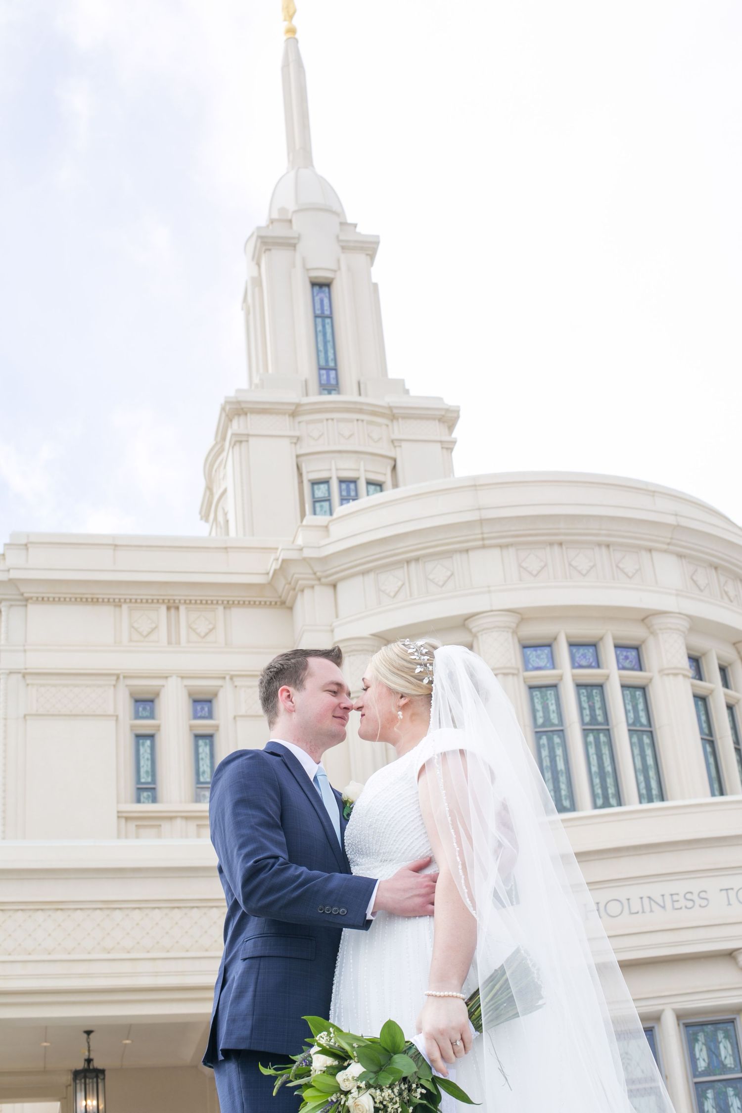 Elegant white temple building with spire against cloudy sky.