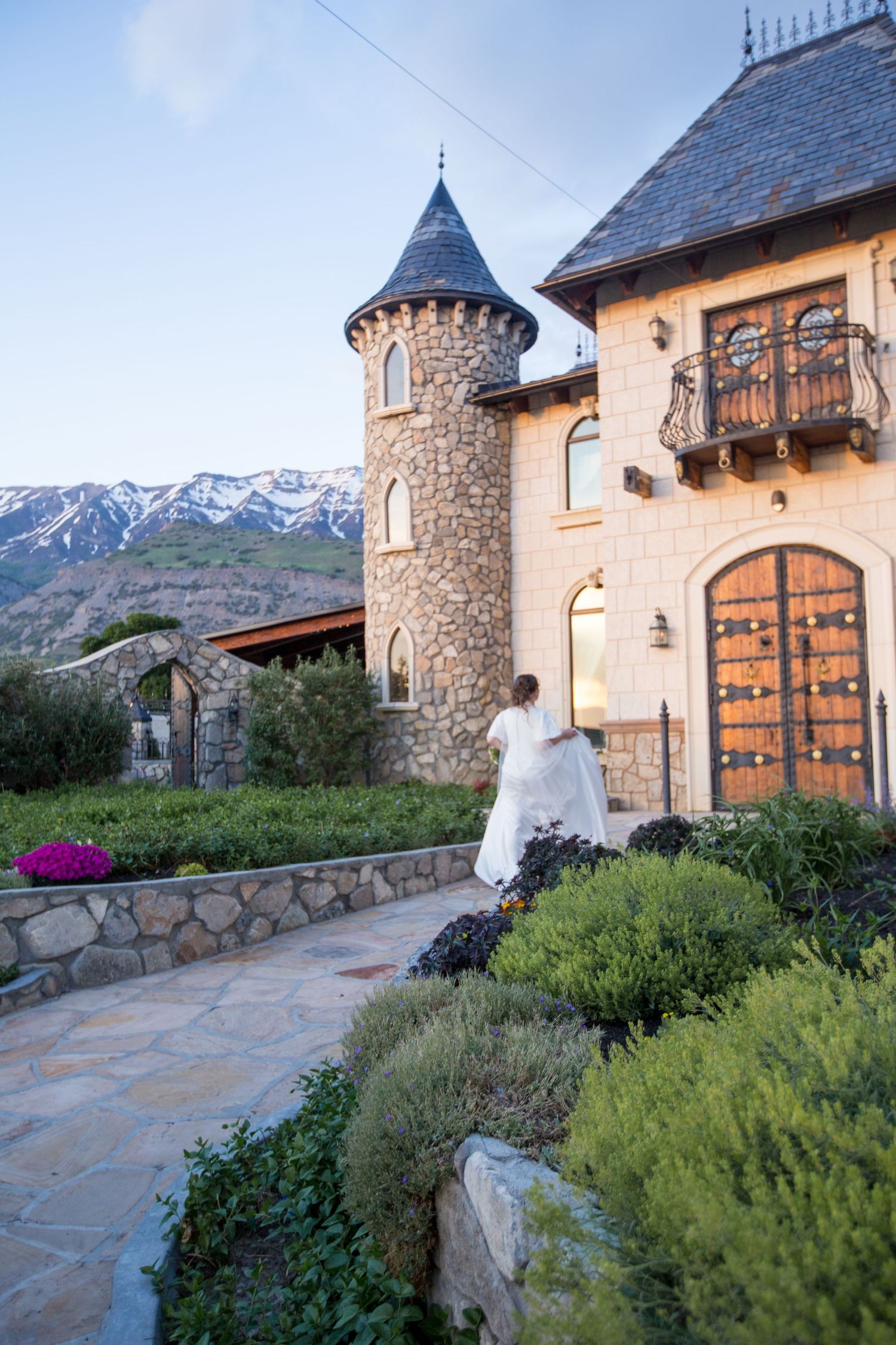 Stone castle venue with mountain backdrop and manicured garden landscaping.