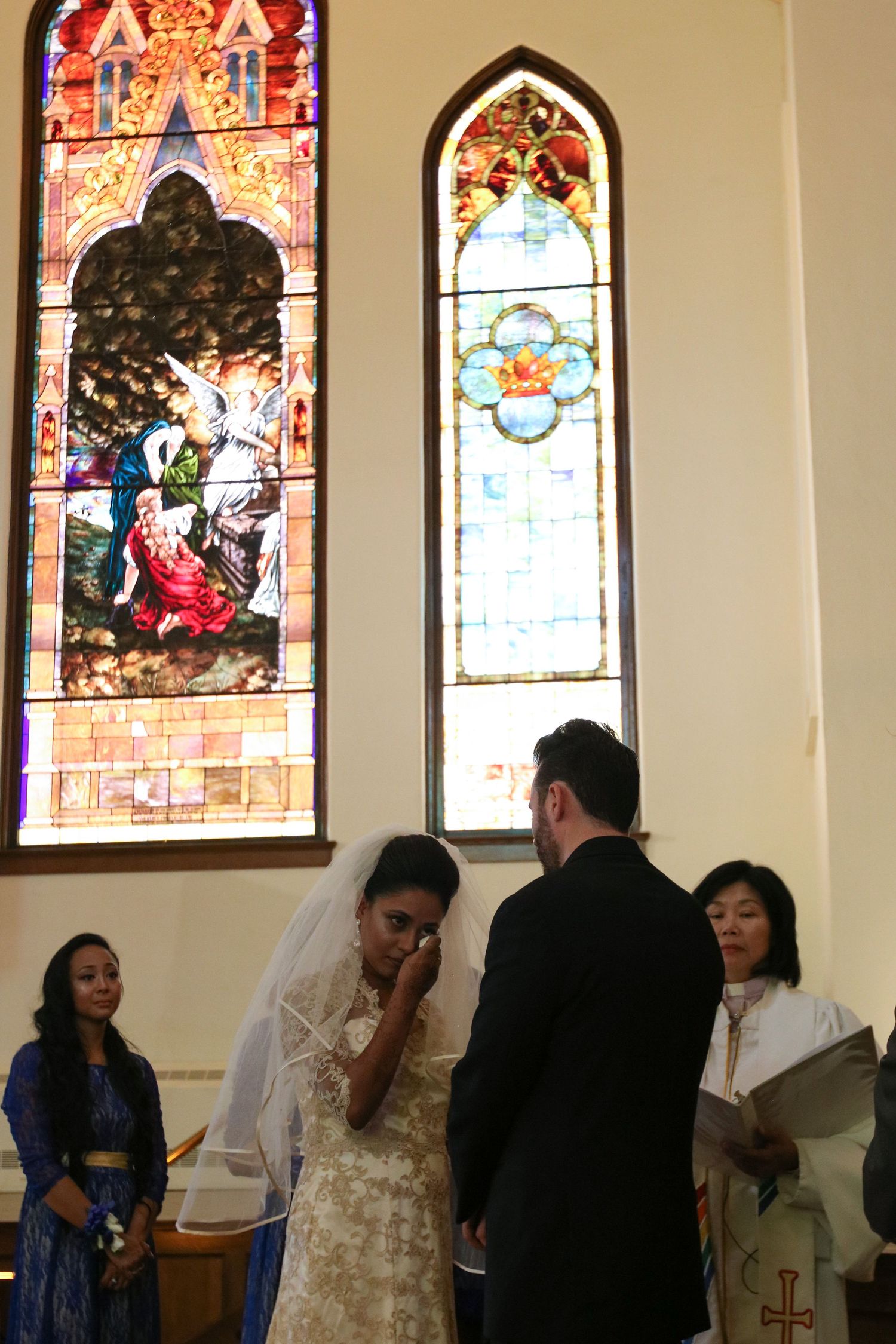 Church interior with beautiful stained glass windows and people gathering for a ceremony.