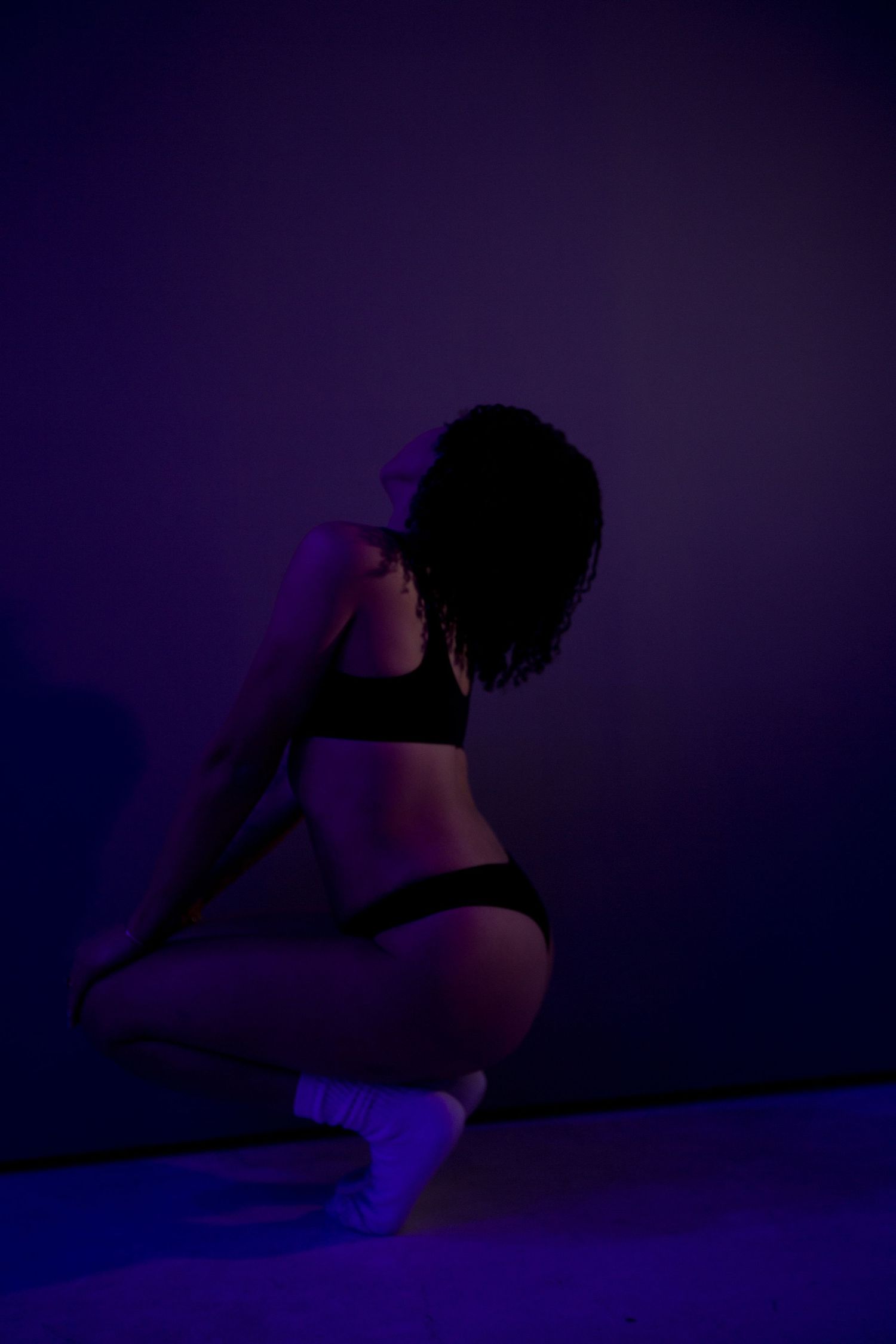 Artistic silhouette photo series in dark purple lighting showing graceful poses against a shadowy background.